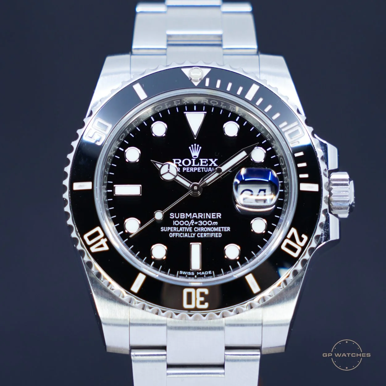 Close-up of a black dial Rolex Submariner watch with stainless steel bracelet, rotating bezel, and a date window at 3 o'clock with a magnifier. The watch face displays the Rolex logo, and the text 'SUBMARINER, 1000ft = 300m, SUPERLATIVE CHRONOMETER, OFFICIALLY CERTIFIED'.