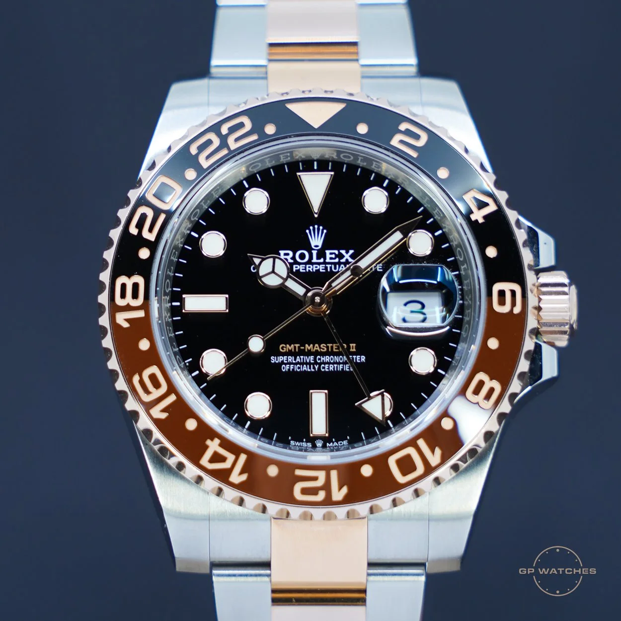 Close-up of a Rolex GMT-Master II wristwatch with a black dial, gold and silver bezel, and a two-tone metal band, displaying the date and GMT hand.