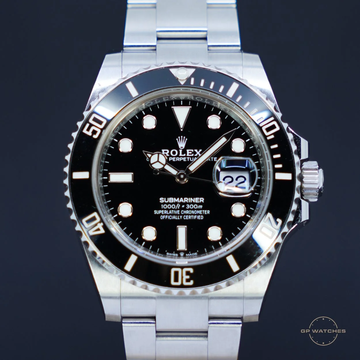 Close-up of a Rolex Submariner watch with a black dial, luminous markers, date window at 3 o'clock, and a rotating bezel, against a dark background.