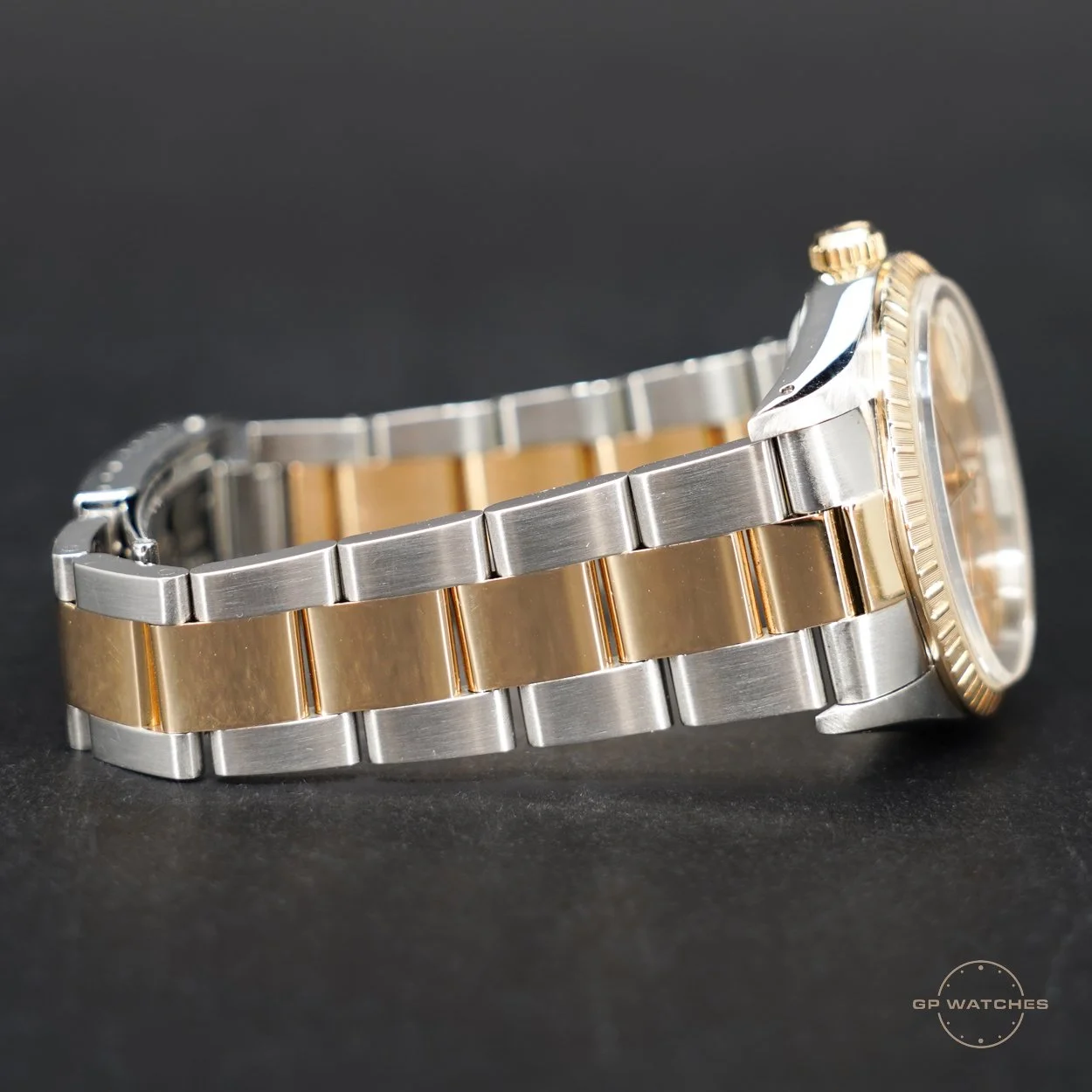A two-tone metal luxury wristwatch with a stainless steel and gold bracelet, set against a black background.