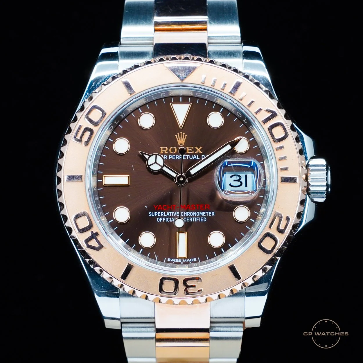 A Rolex Yacht-Master watch with a brown dial, gold bezel, and stainless steel and gold bracelet. The watch shows the date as the 31st.