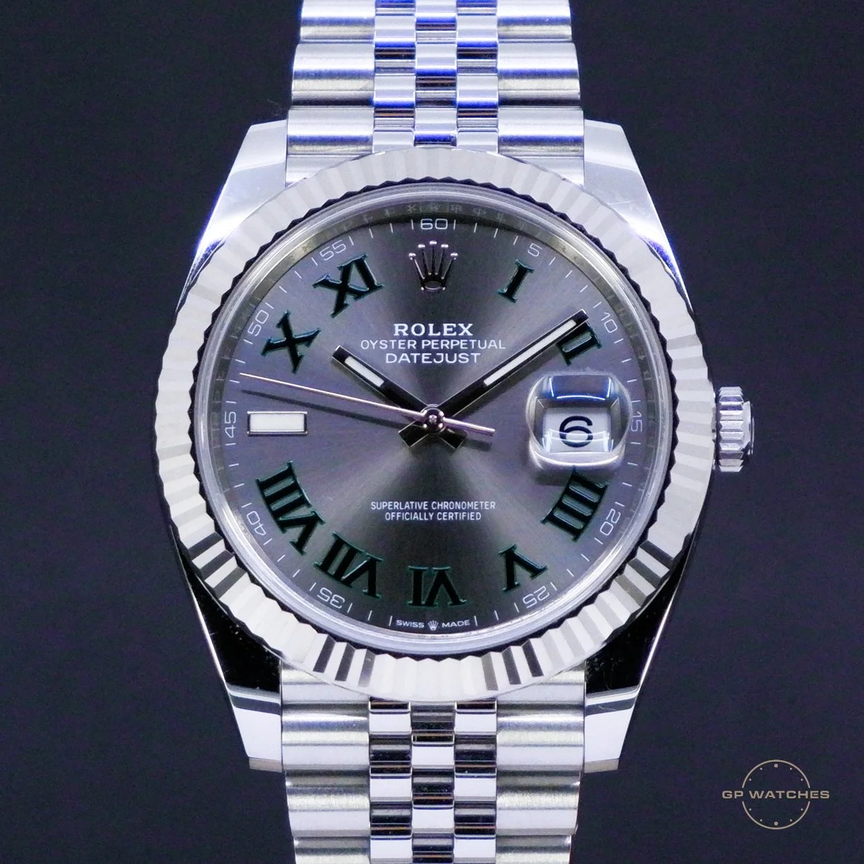 A silver Rolex Oyster Perpetual Datejust wristwatch with Roman numerals, a date window at 3 o'clock, and a fluted bezel, on a metal bracelet.