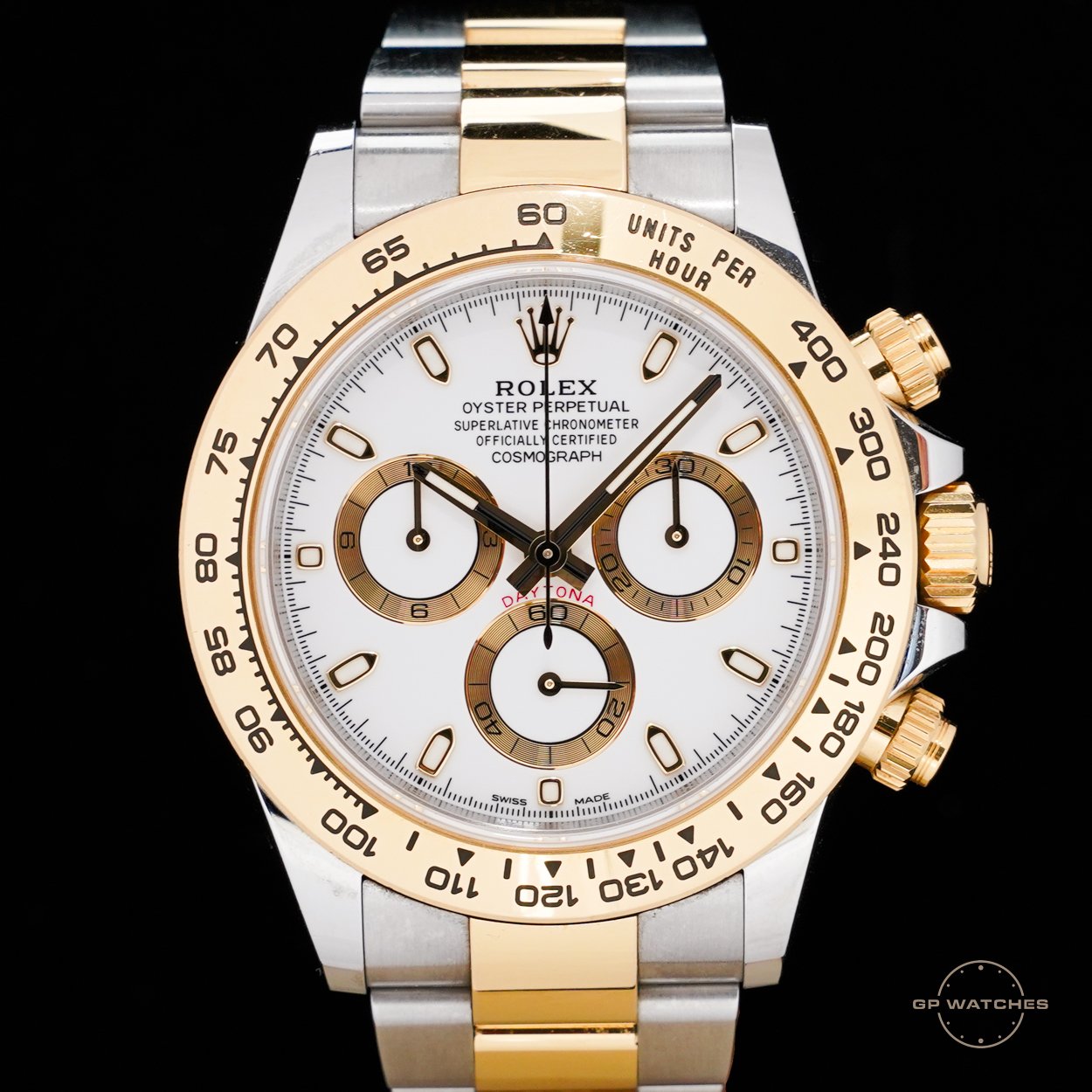 Close-up of a Rolex Daytona wristwatch with a white dial, gold bezel, and two-tone metal band, featuring three subdials and black and gold accents.