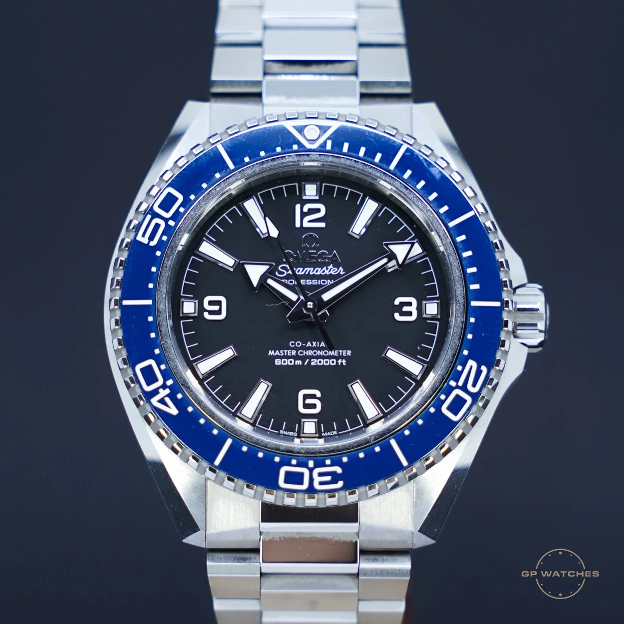 Close-up of a luxury Omega Seamaster Diver watch with a black dial, blue bezel, and silver bracelet.