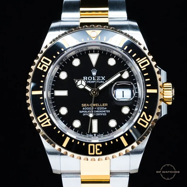 Rolex Sea-Dweller watch with black dial, gold and stainless steel bracelet, and date window.