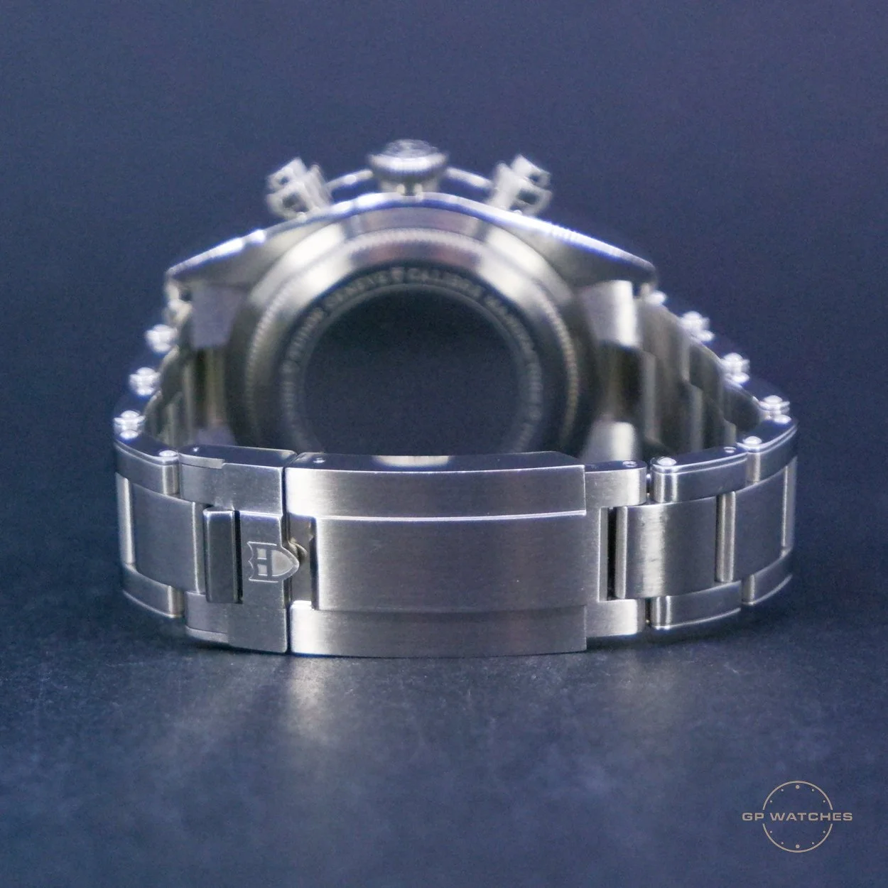 Silver wristwatch with metal bracelet, displayed on a dark surface, taken from the back showing the watch case and bracelet.