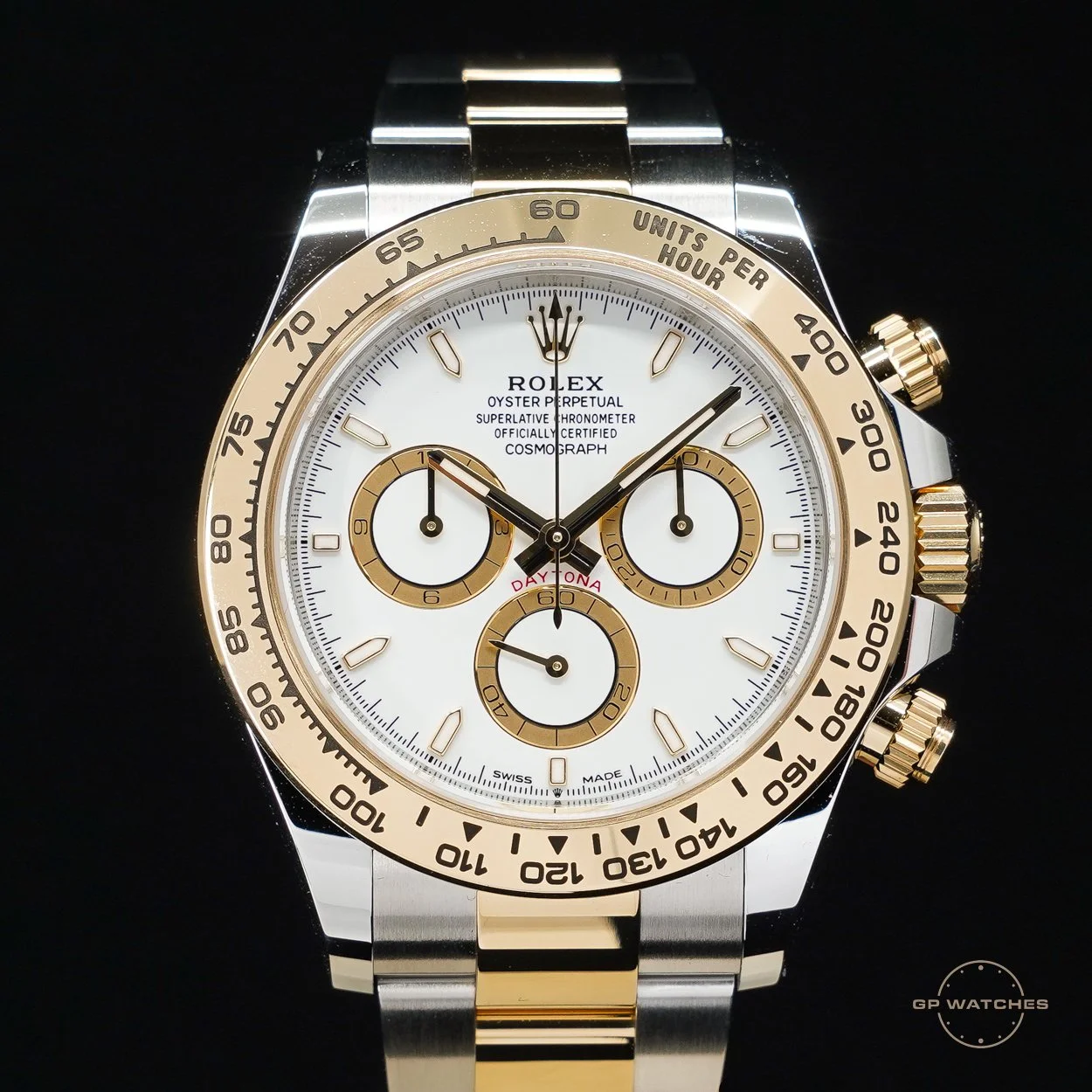 A Rolex Oyster Perpetual Cosmograph Daytona wristwatch with a white dial, gold and silver band, and gold bezel, featuring subdials, chronograph functions, and markers.