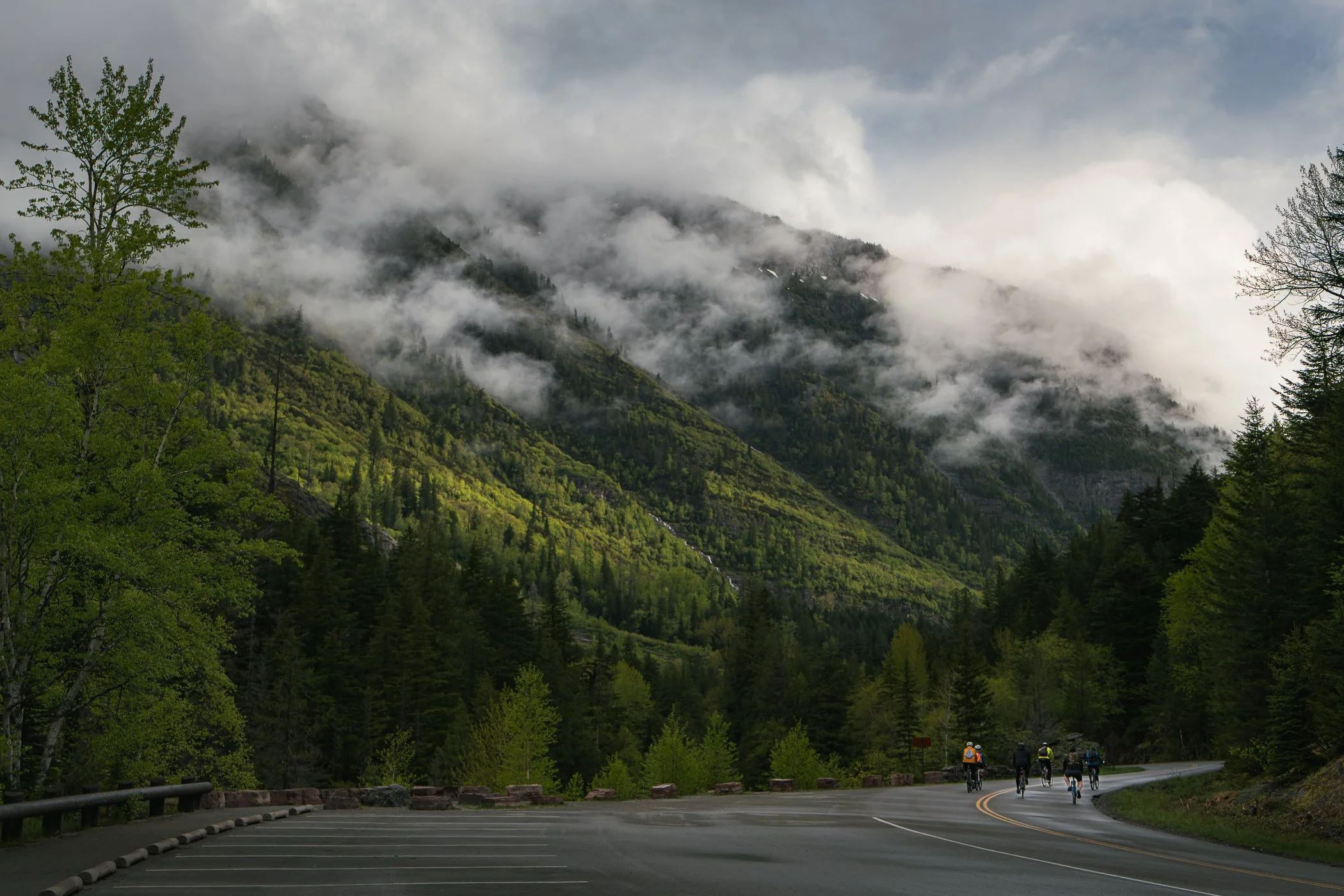 Cyclist riding along Going-to-the-Sun Road in Glacier National Park with mountain vistas in the background.