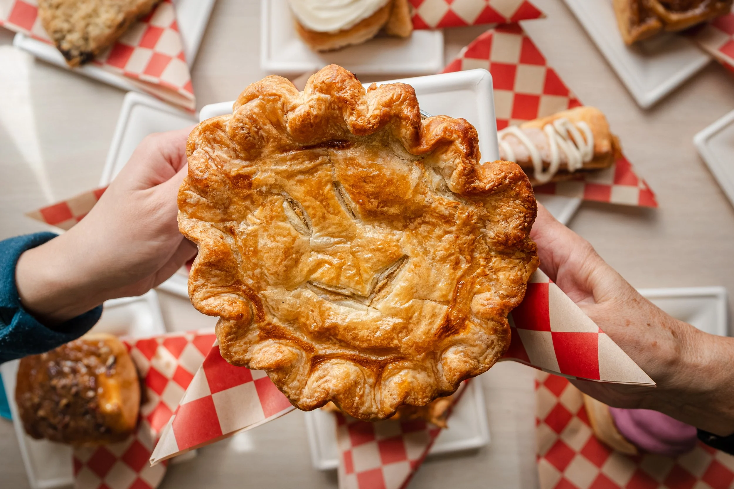 A hand pie held over an overhead spread, shot for a bakery content library.
