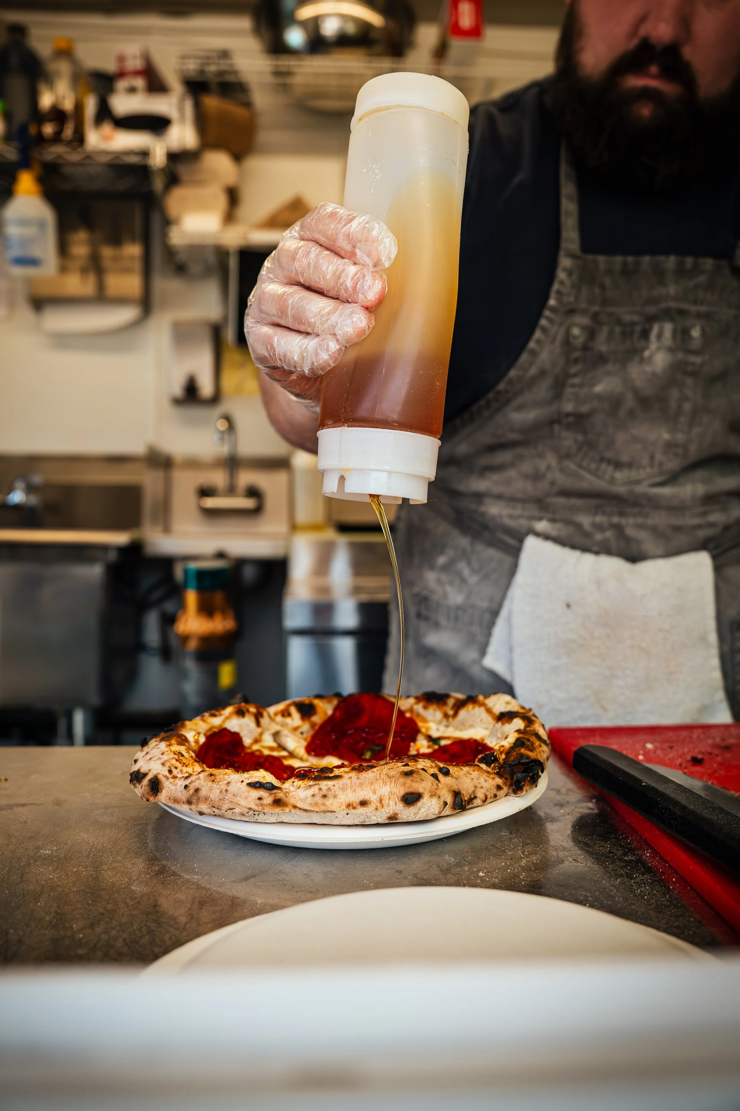 man squeezing hot honey on pizza in food truck called Fire and Dough in Kalispell Montana