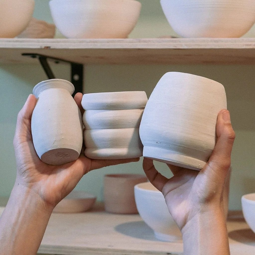 Hands holding up completed pieces of ceramic artwork