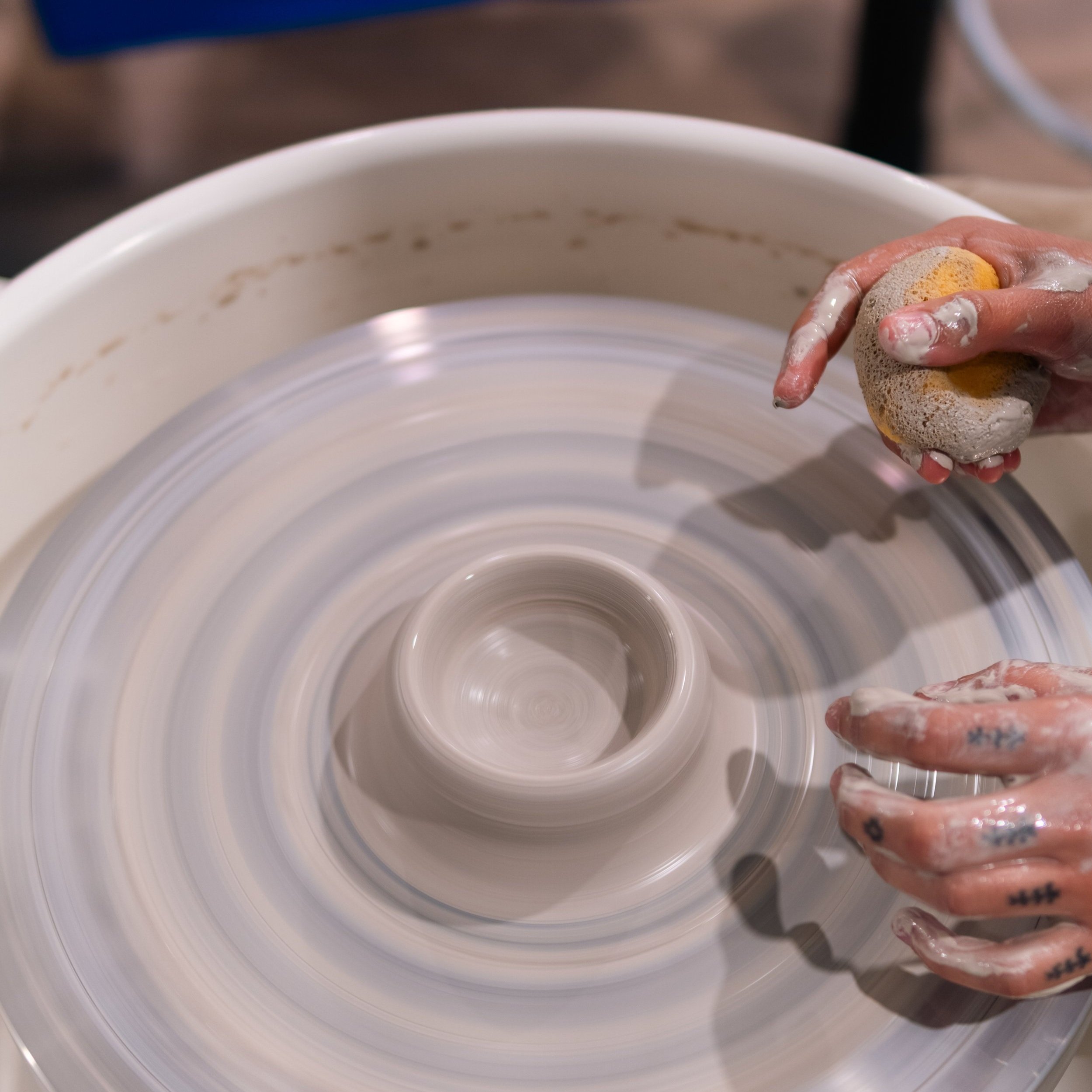 Image of pottery wheel and hands making a bowl