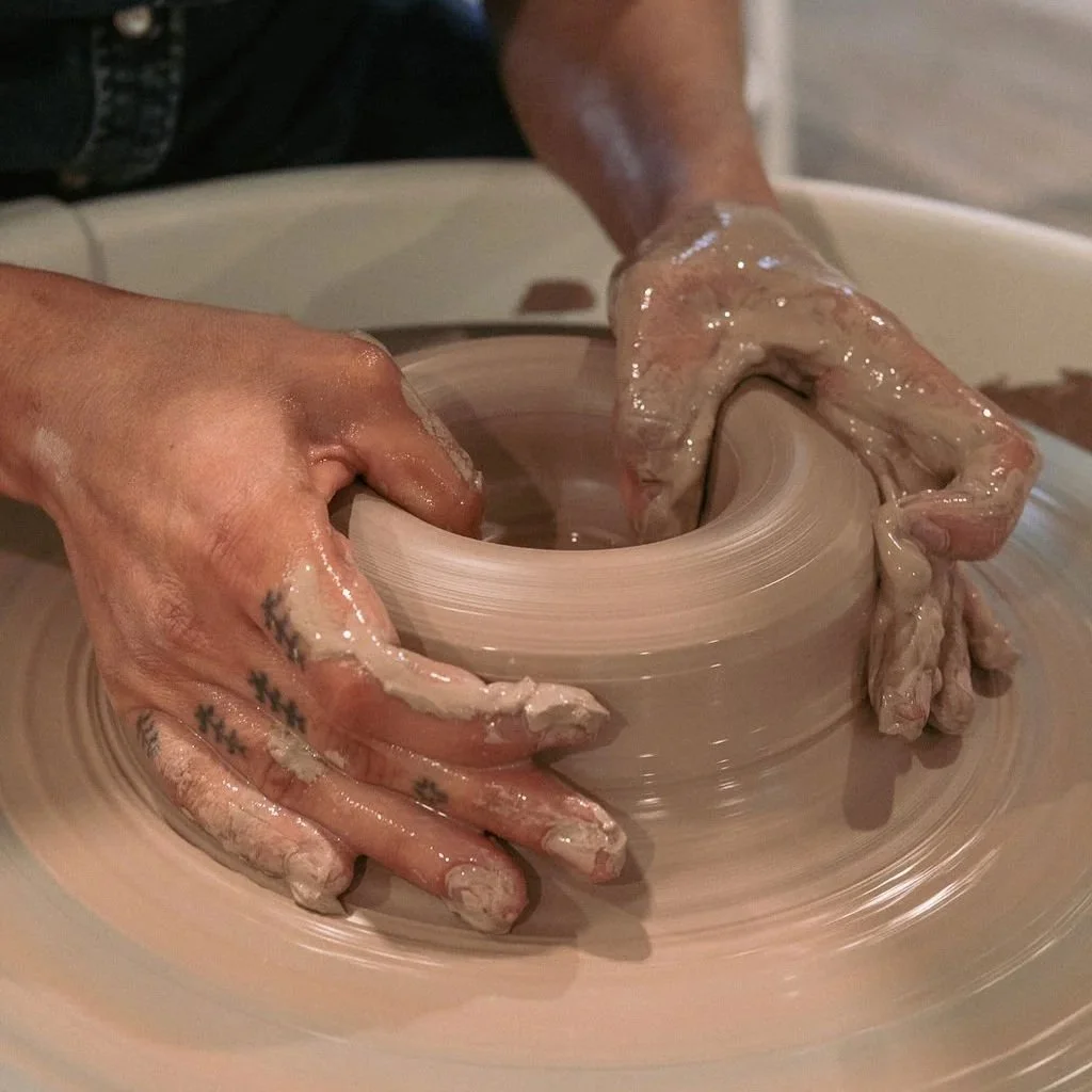 Set of hands pulling clay on a potters wheel