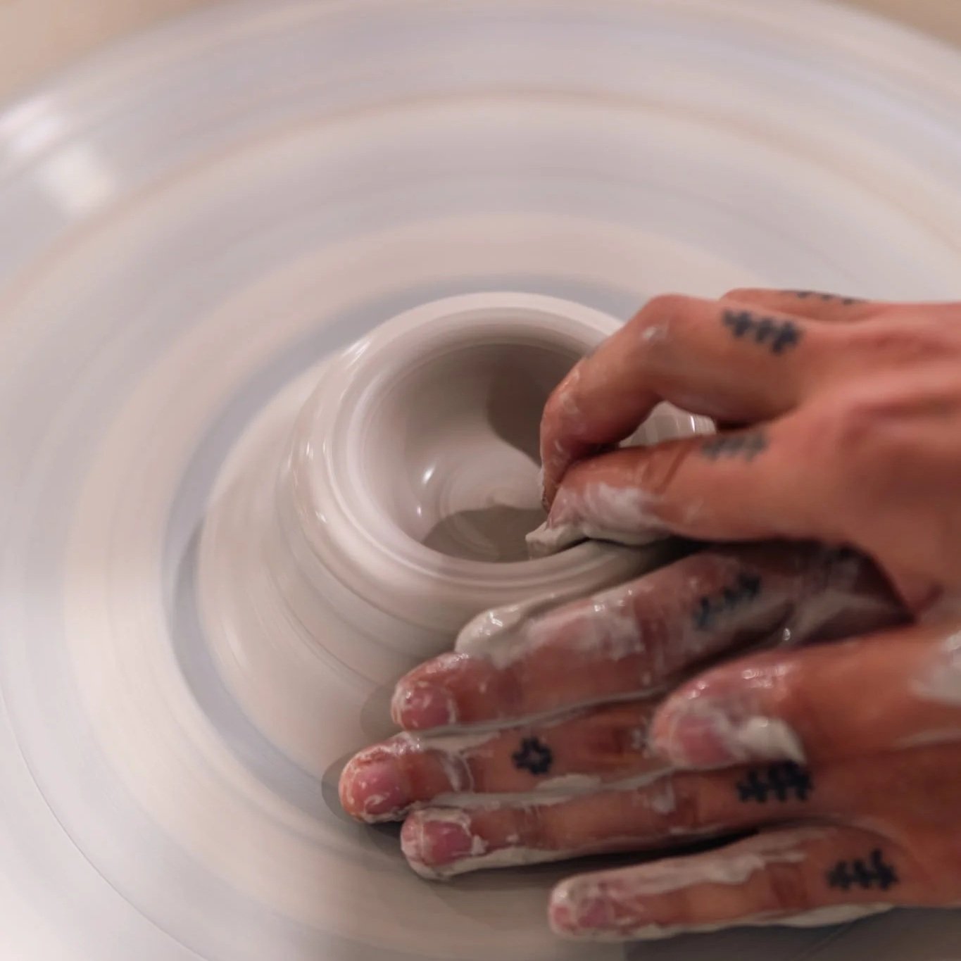 Set of hands pulling clay on a potters wheel