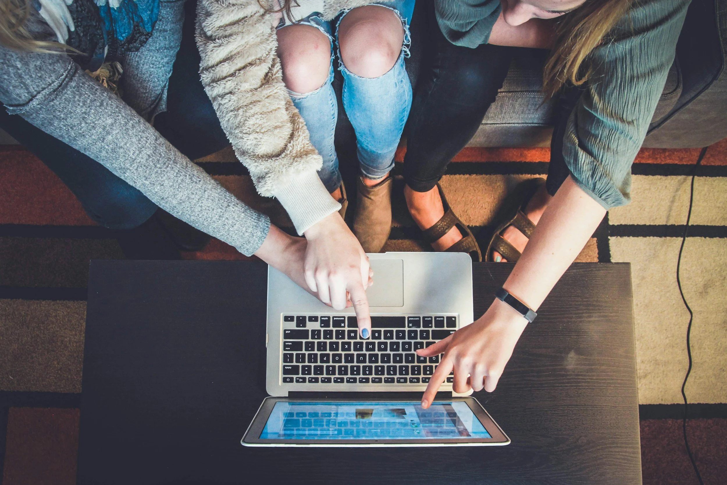 People's hands pointing at laptop