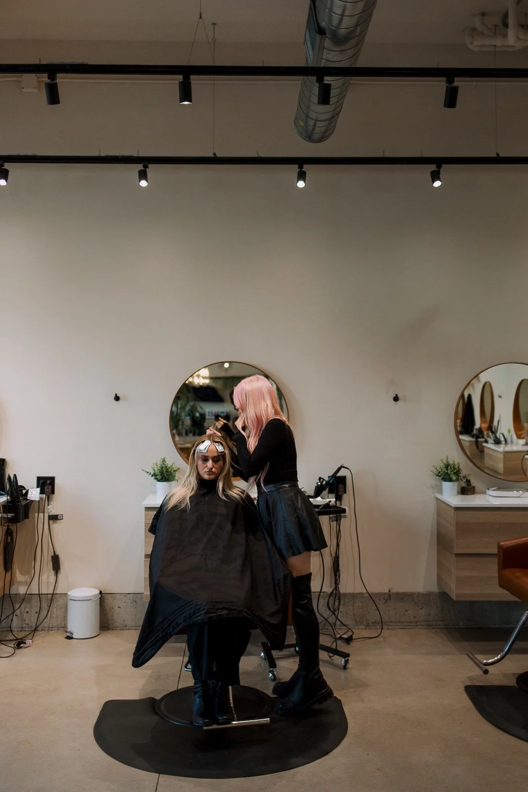 hairstylist with pink hair applying highlights to a client.