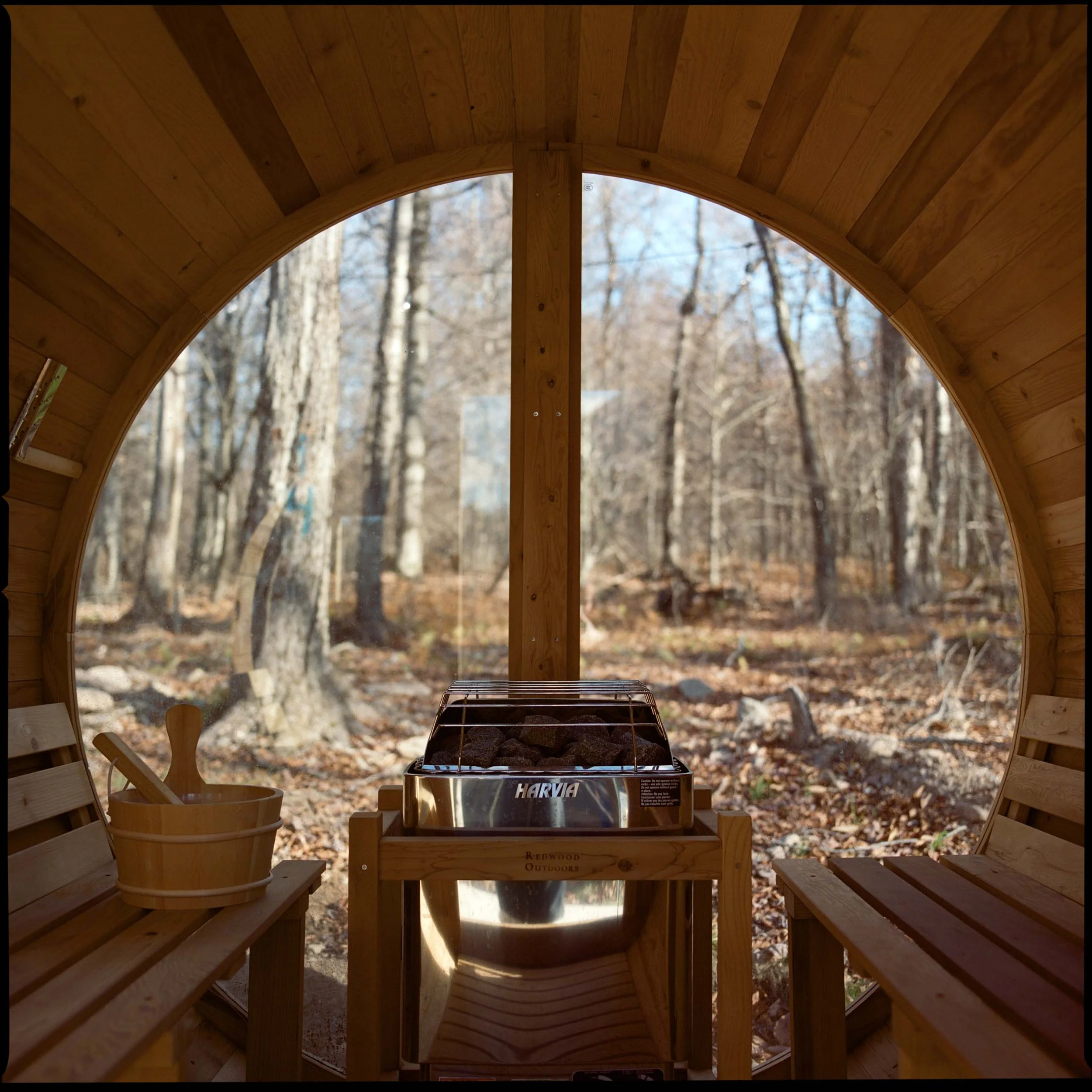 Inside the Redwood barrel sauna at The Glove, round window to the forest