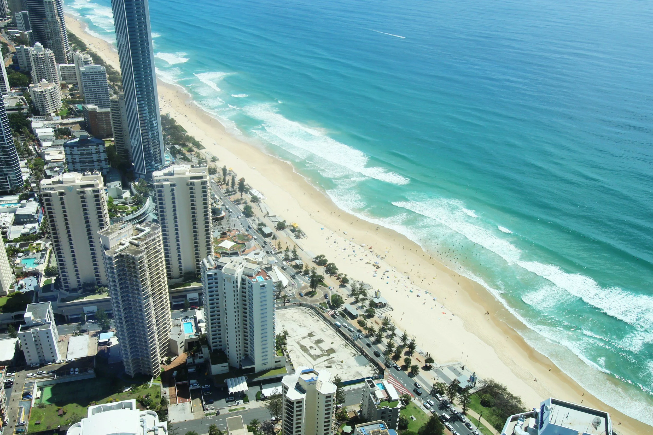 Aerial view of a coastal city with skyscrapers and a beach with waves.