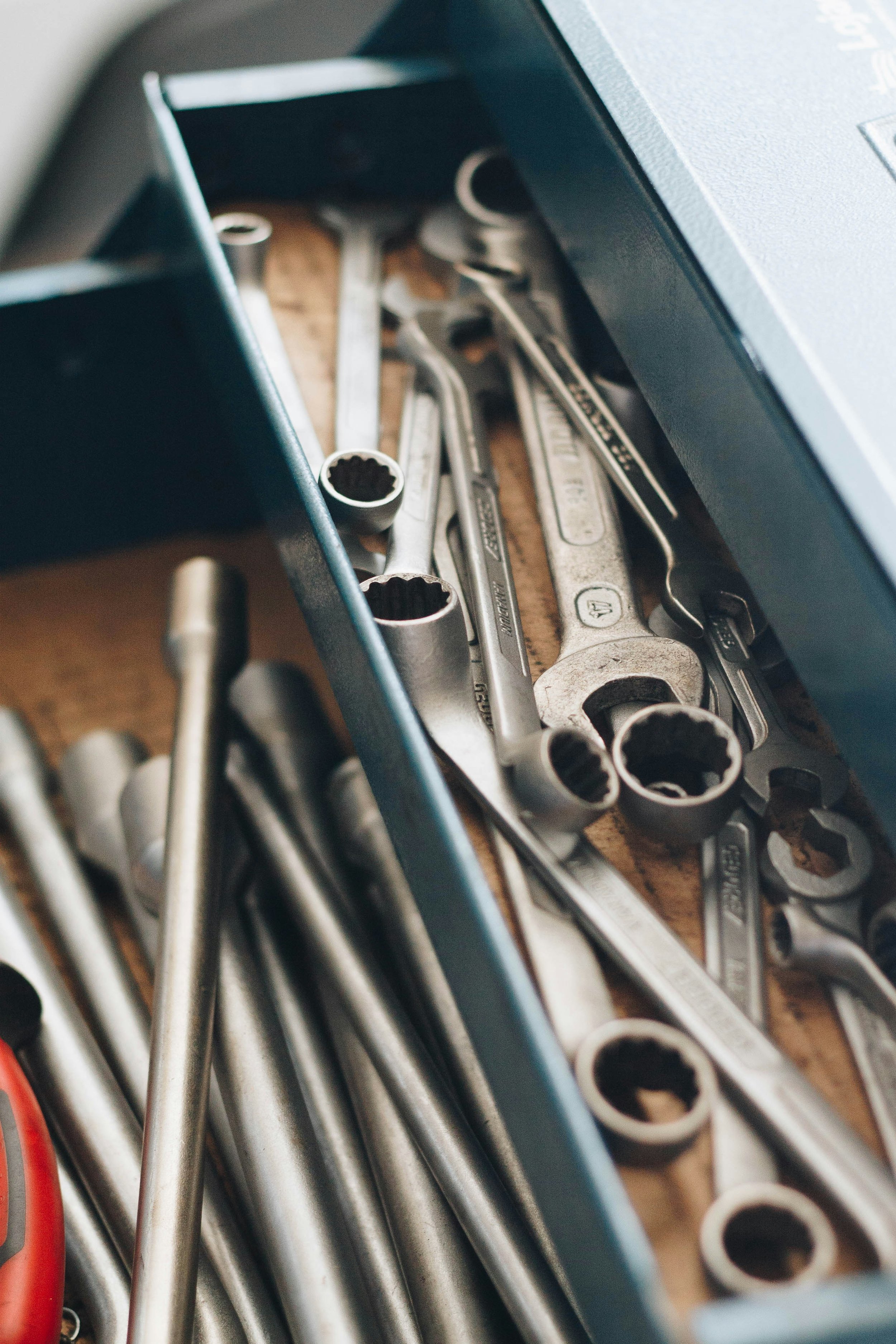 Open toolbox drawer with various wrenches and metal rods.