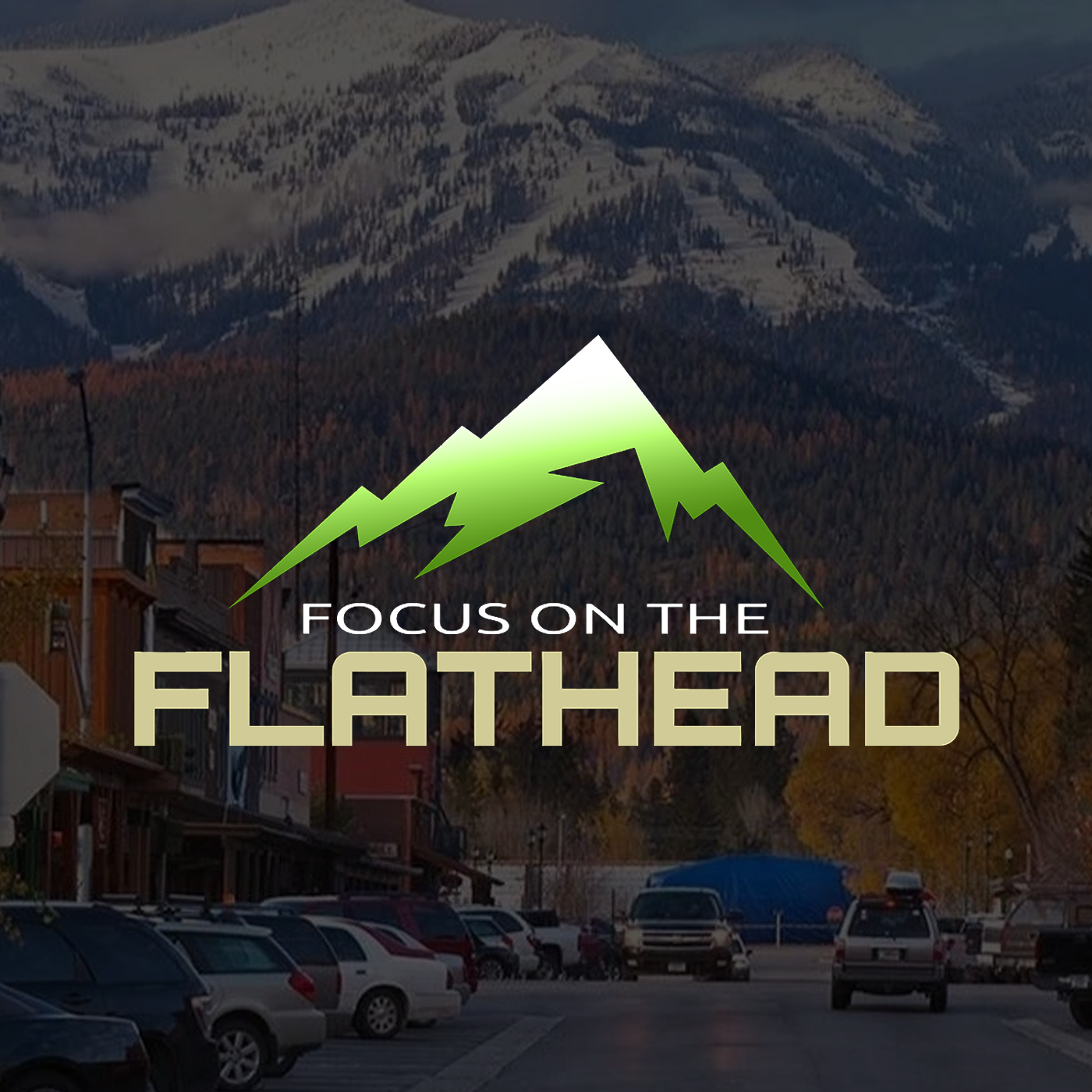 A mountain scene with snow-capped peaks in the background, a small town with wooden buildings and cars in the foreground, and a logo of a green mountain with the text 'Focus on the Flathead' overlaying the image.