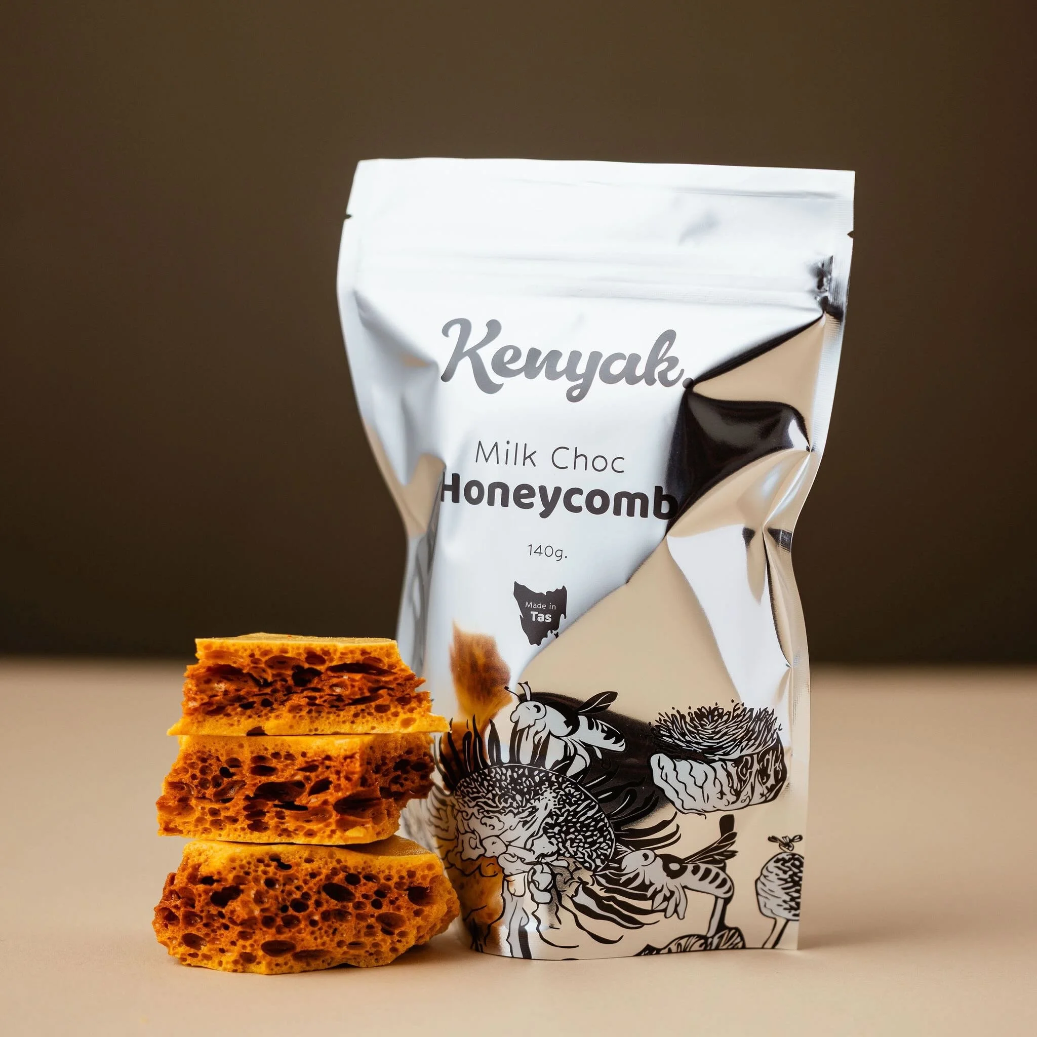 Bag of Kenyak honeycomb milk chocolate next to three pieces of honeycomb.