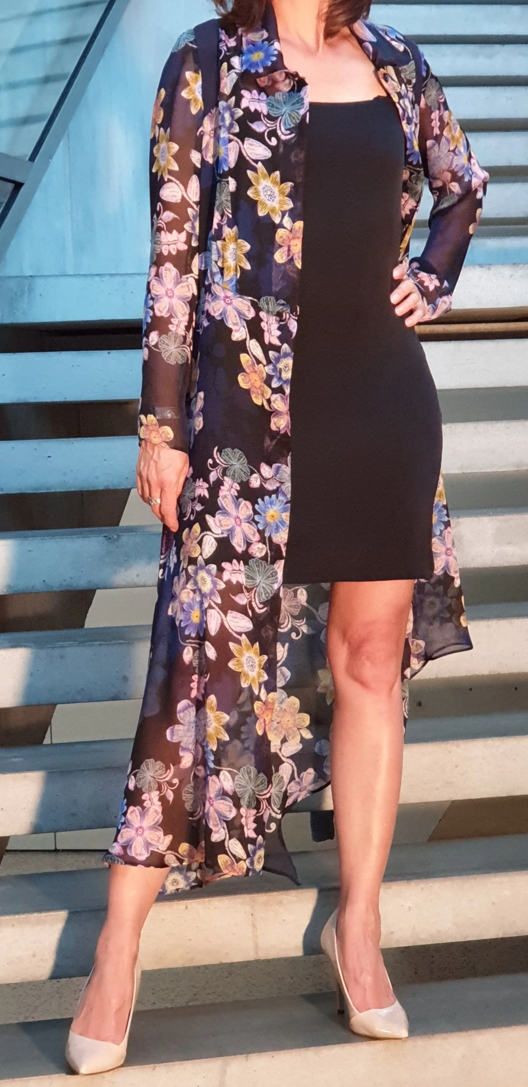 Frau auf Treppe, trägt schwarzes Kleid, langen transparenten Kimono mit Blumenmuster, weiße High Heels.