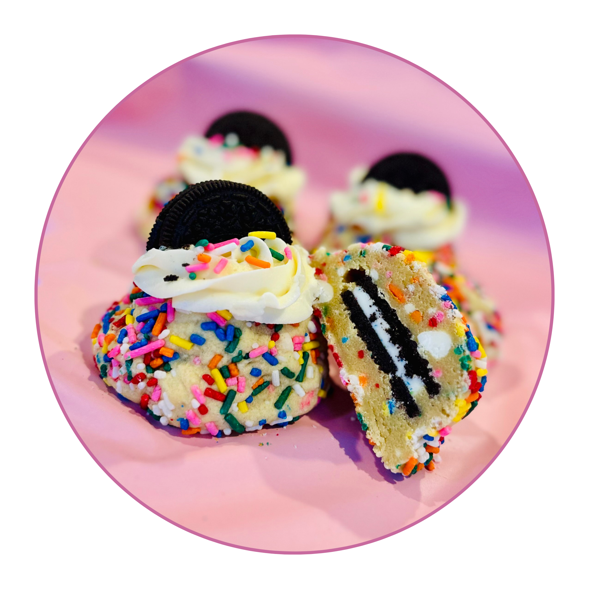 Close-up of rainbow sprinkled cupcakes with Oreo cookie decorations on a pink plate.