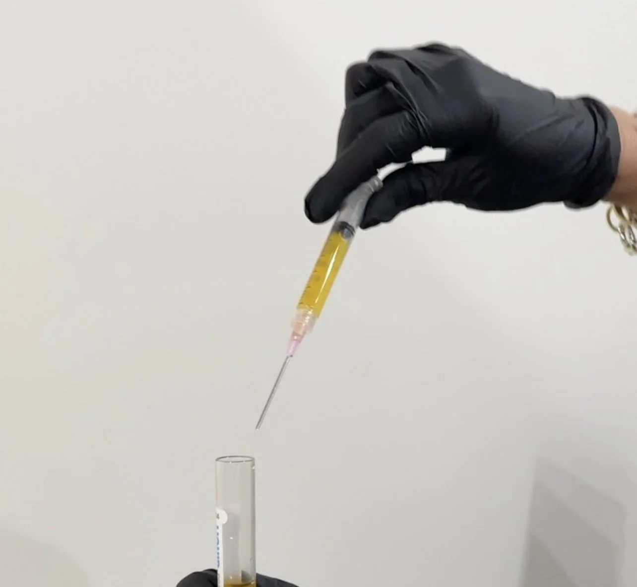 Three test tubes containing blood plasma, red blood cells, and blood serum held in a person's hand