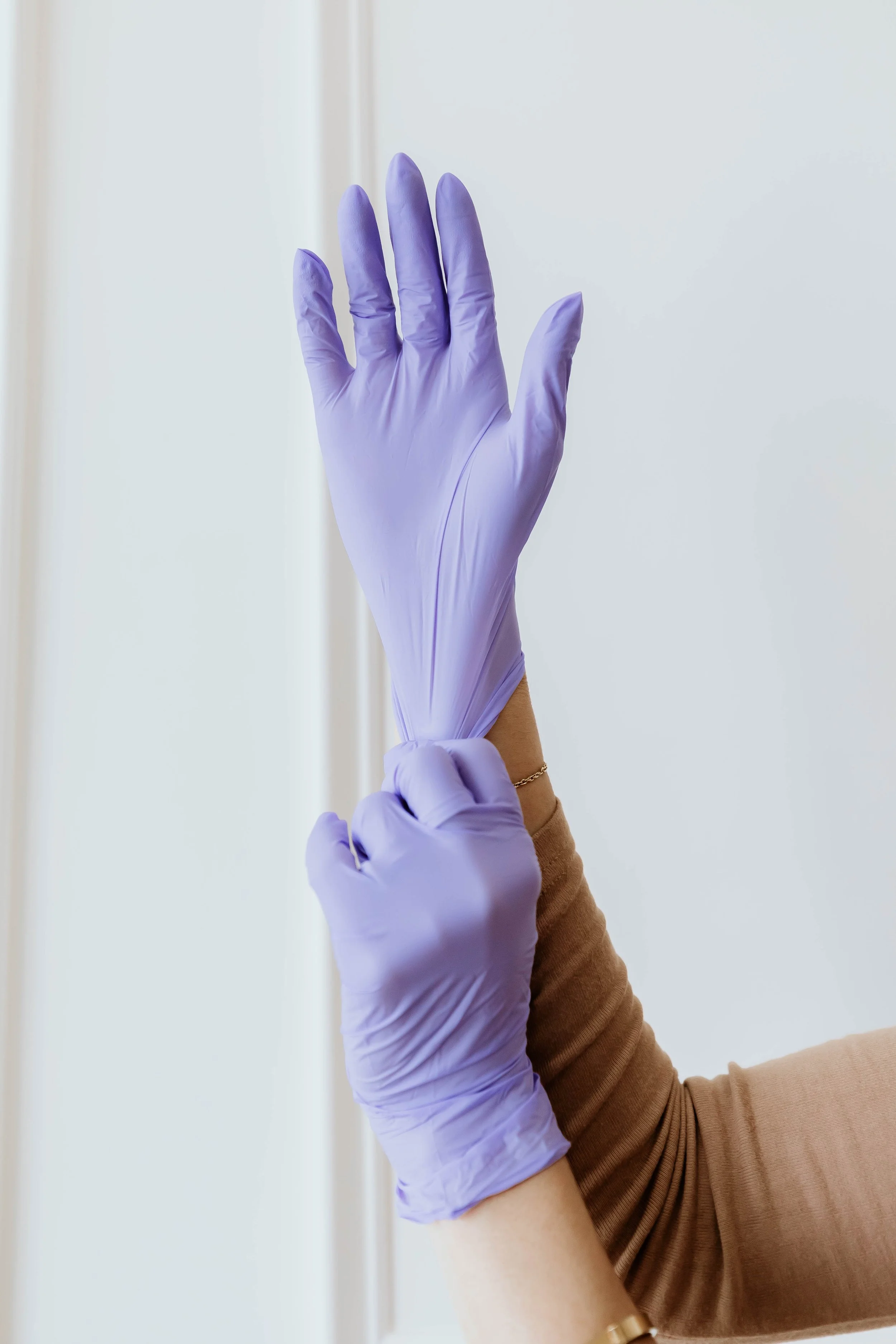 Person wearing purple disposable gloves, preparing to put on or take off the gloves.
