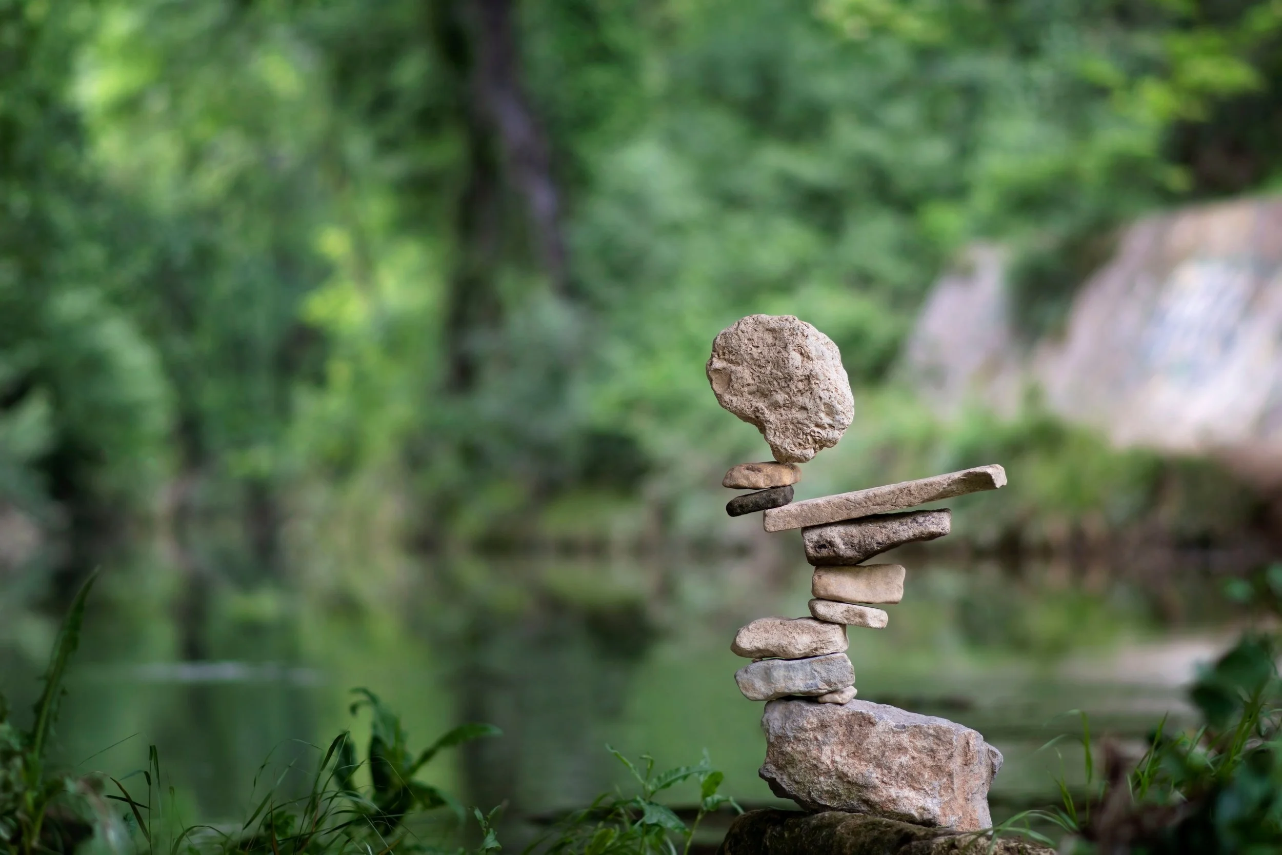 Balancing stones, stacked on top of each other against a green background.