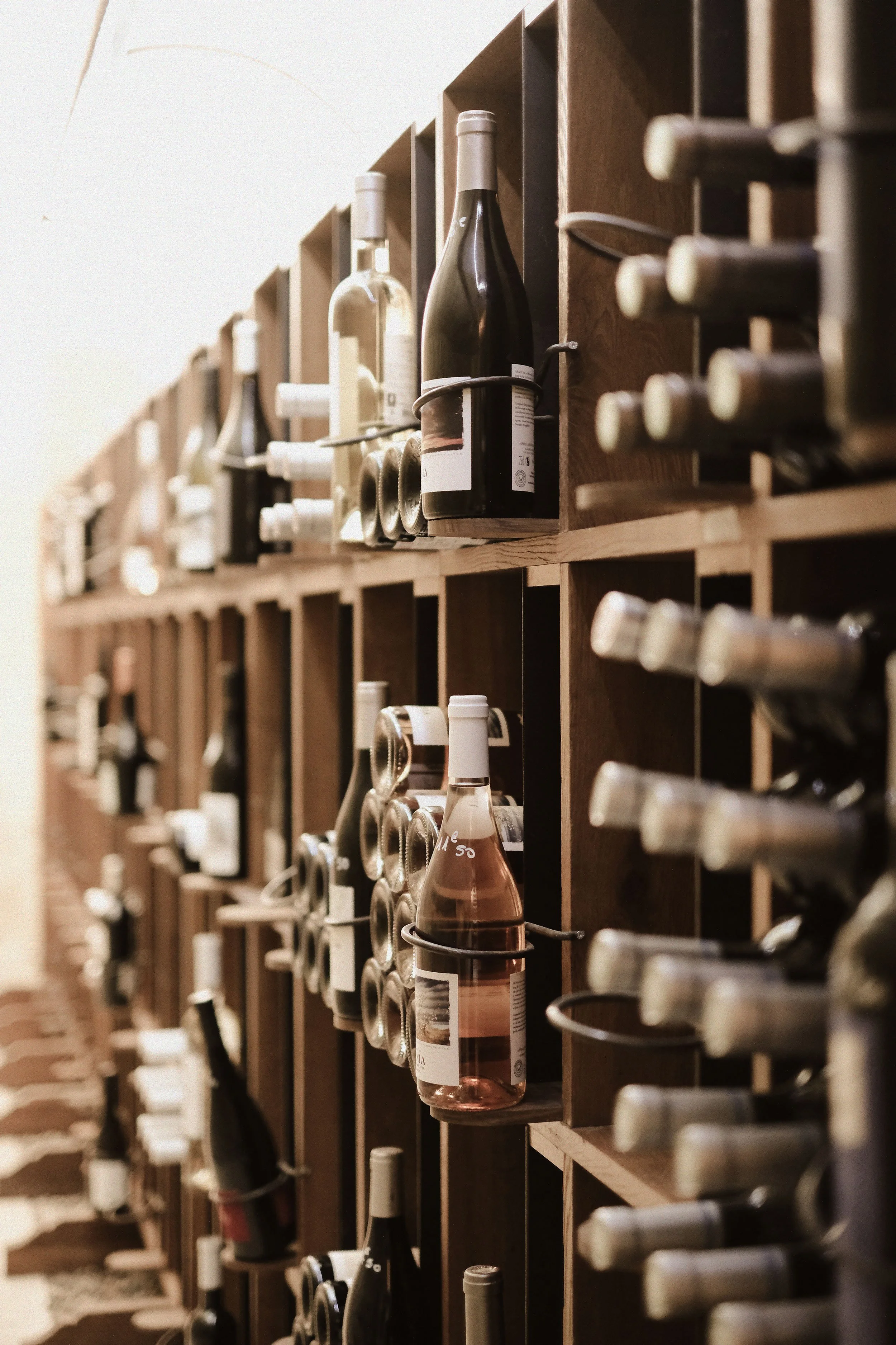 A wooden wine rack filled with various bottles of wine stored horizontally in individual compartments.