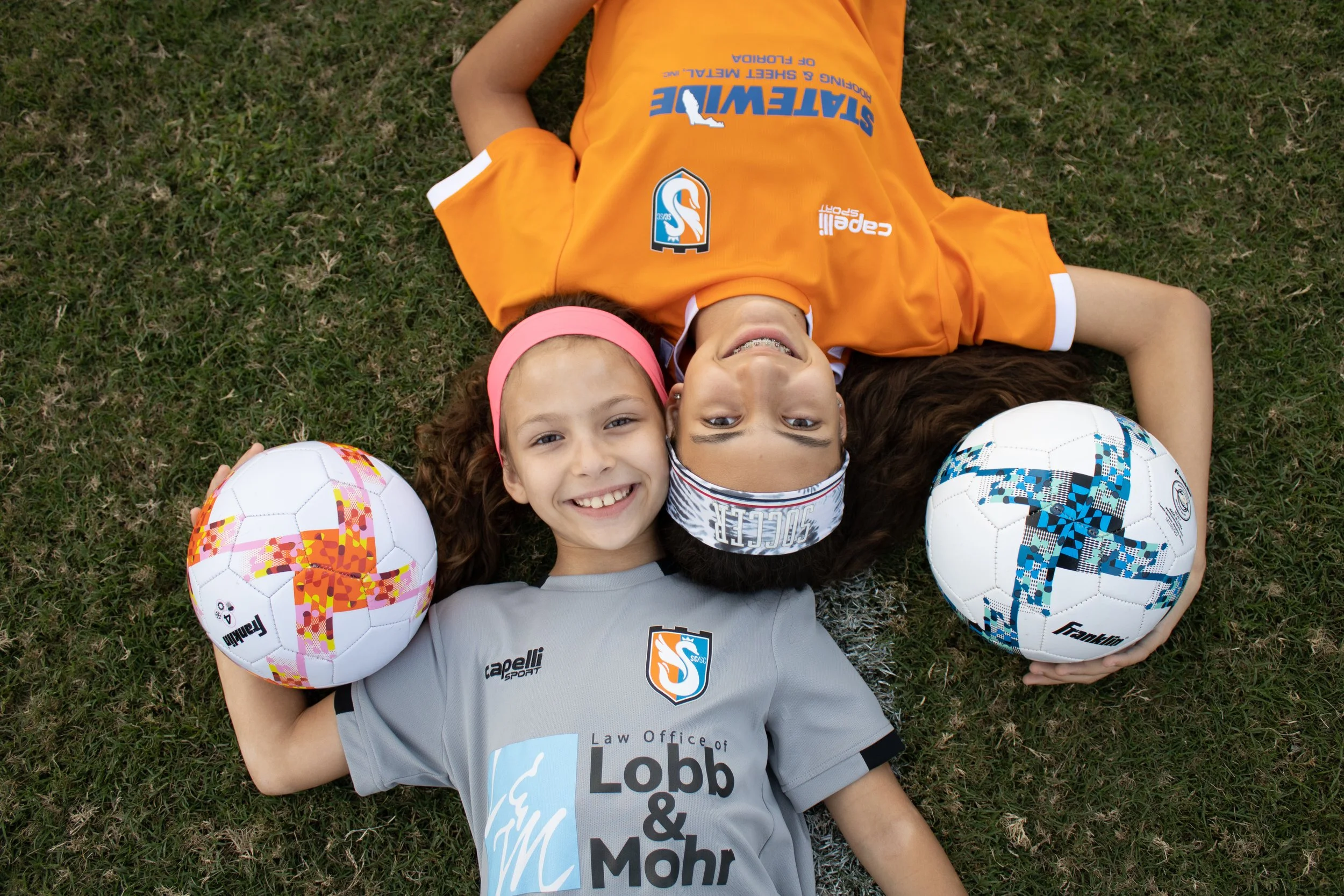 Two young soccer players laying in the grass