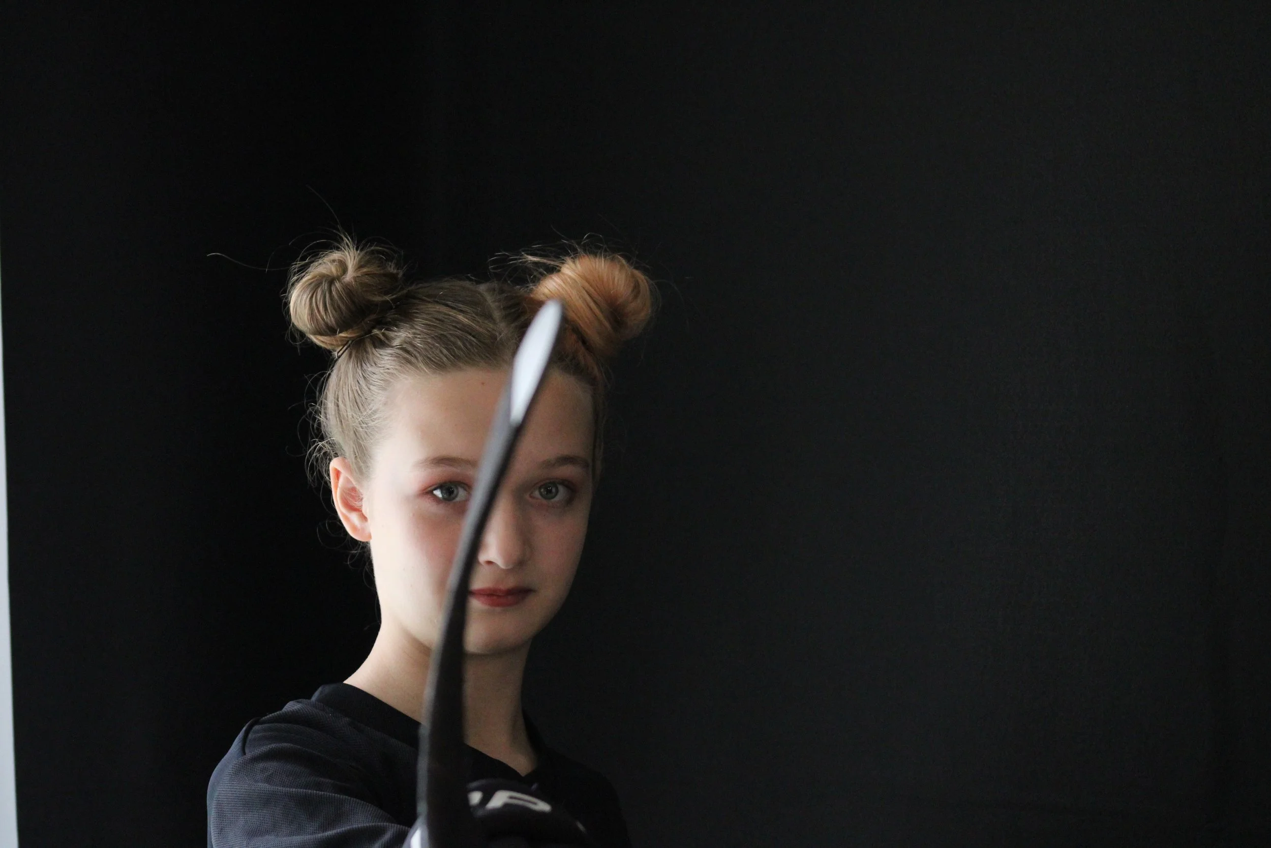 Portrait of blonde teen holding a hockey stick.