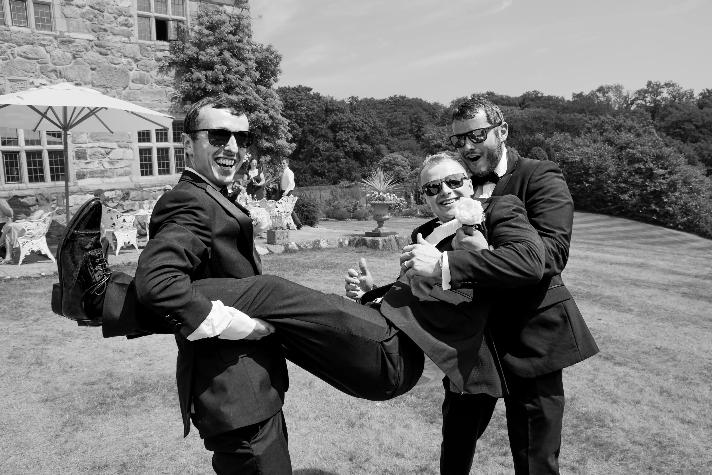 groomsmen-swinging-groom-talhenbont-hall-wedding.webp