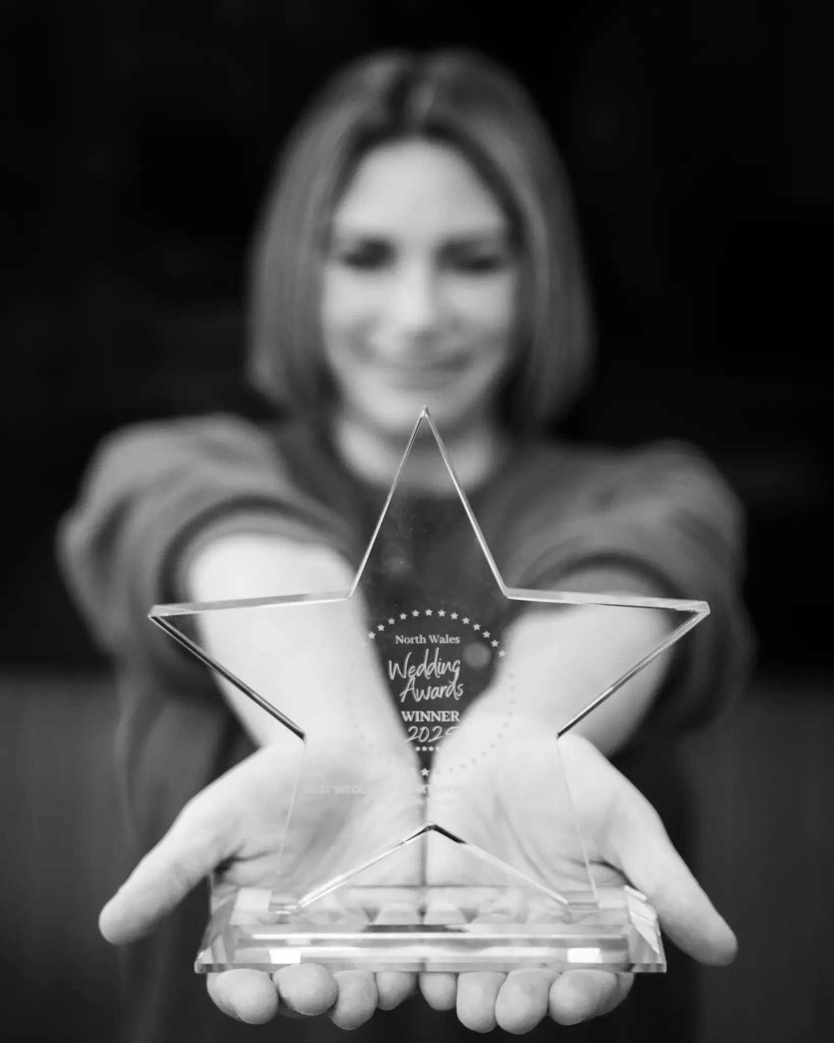 A woman smiling and holding a star-shaped award trophy for the North Wales Wedding Awards 2022.