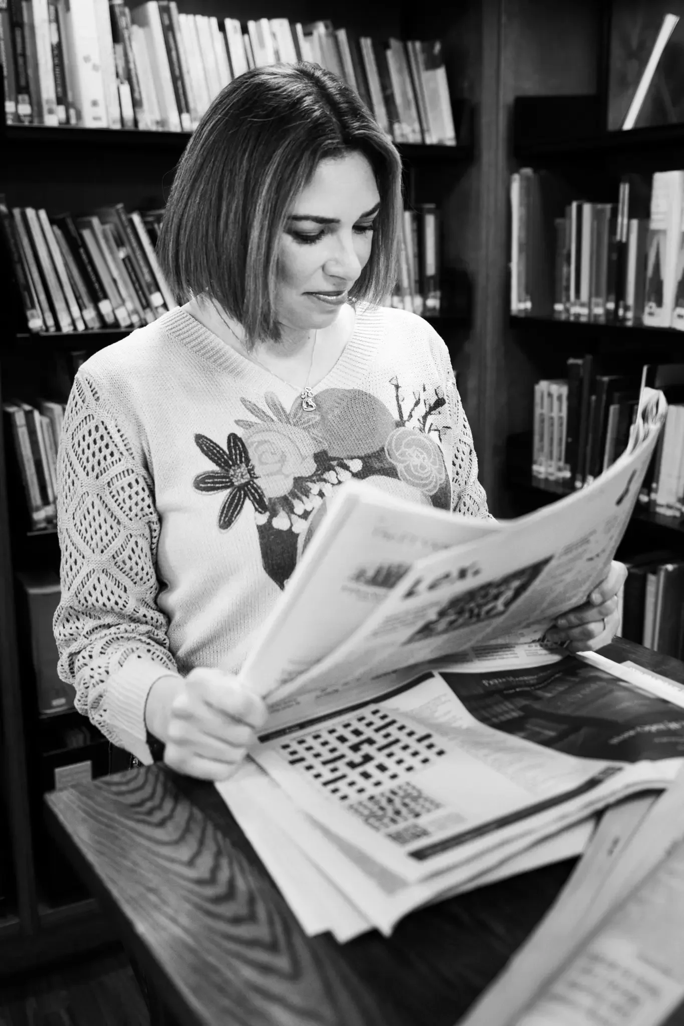 A woman with shoulder-length hair looking at newspapers in a library.