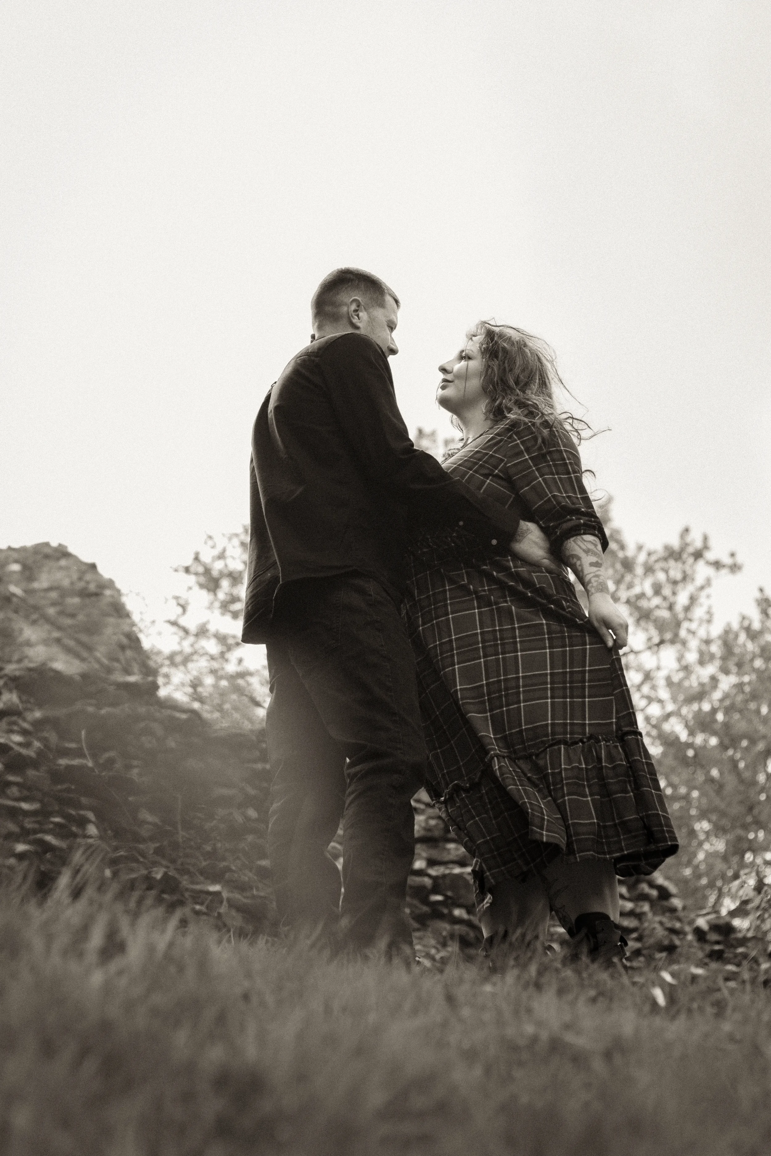 black-and-white-alternative-romantasy-couple-embracing-in-front-of-ruins-ewloe-castle-ewloe-north-wales-low-angle.webp