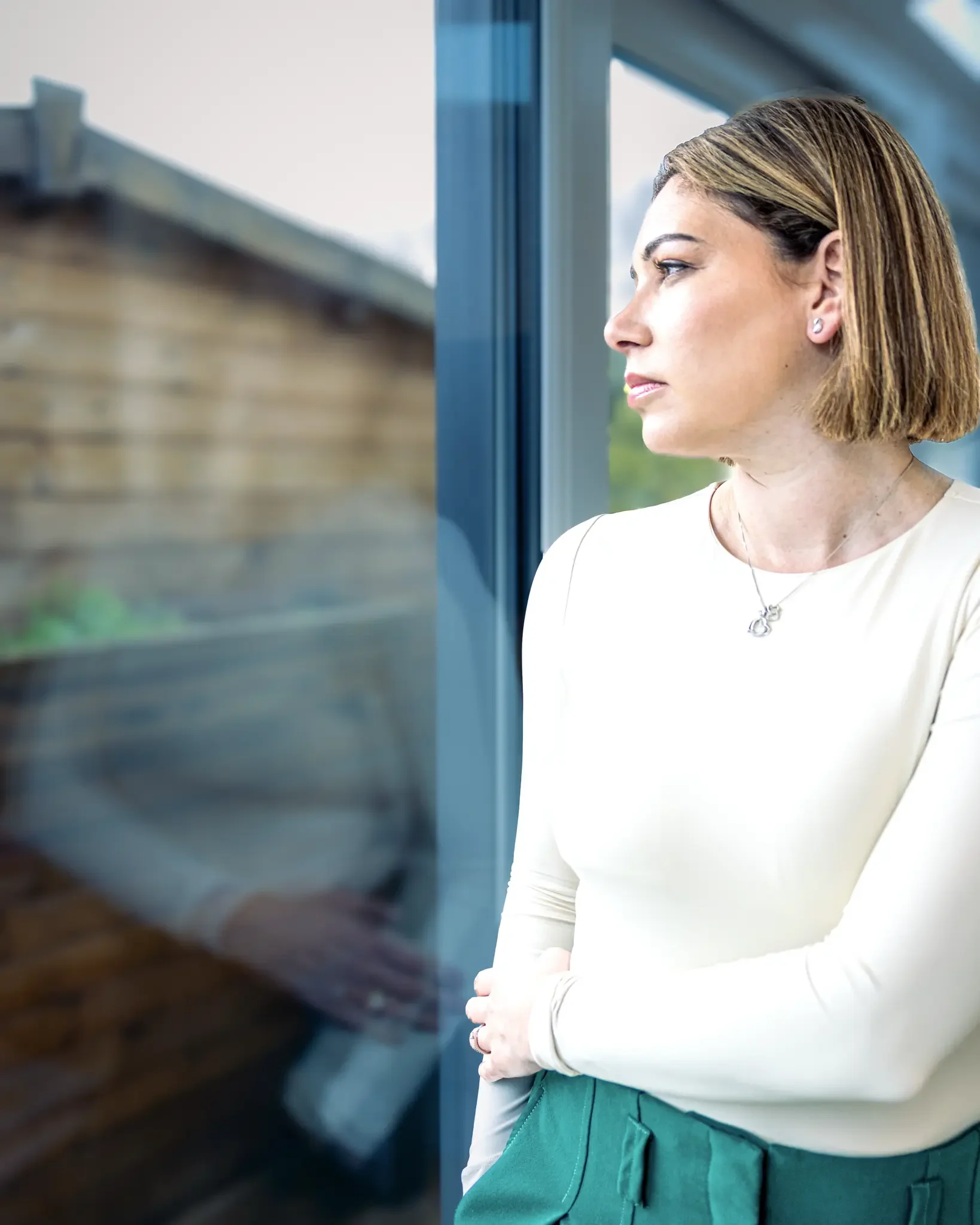 A woman with short brown hair looking out a window.
