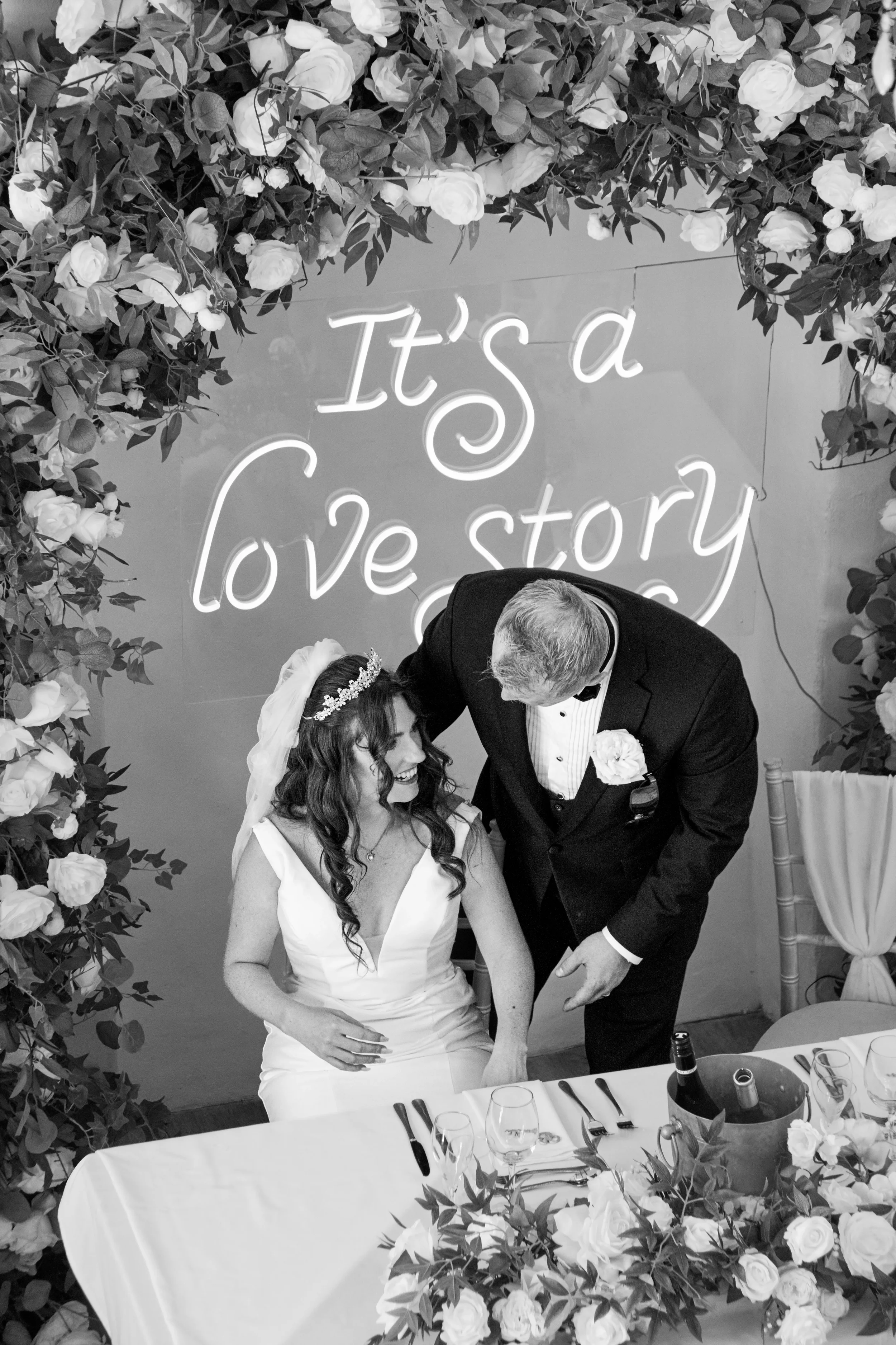 groom-helping-bride-sit-for-wedding-breakfast-talhenbont-hall-wedding.webp
