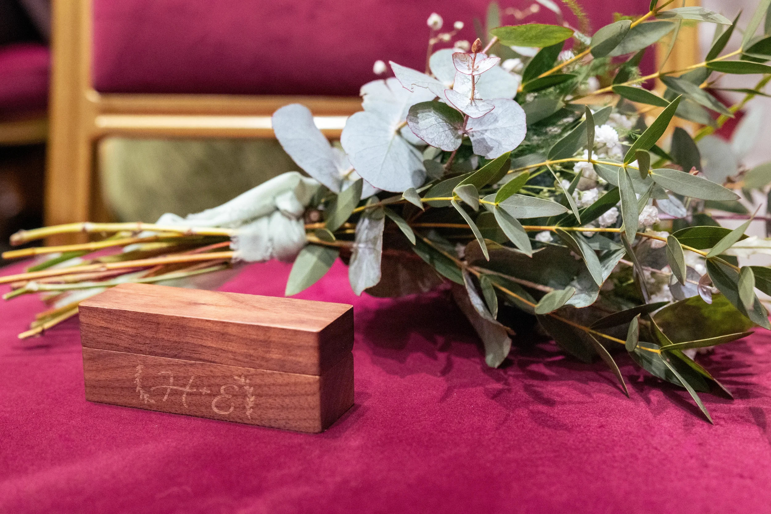 wedding detail with bouquet and engraved ring box on ceremony chair.webp