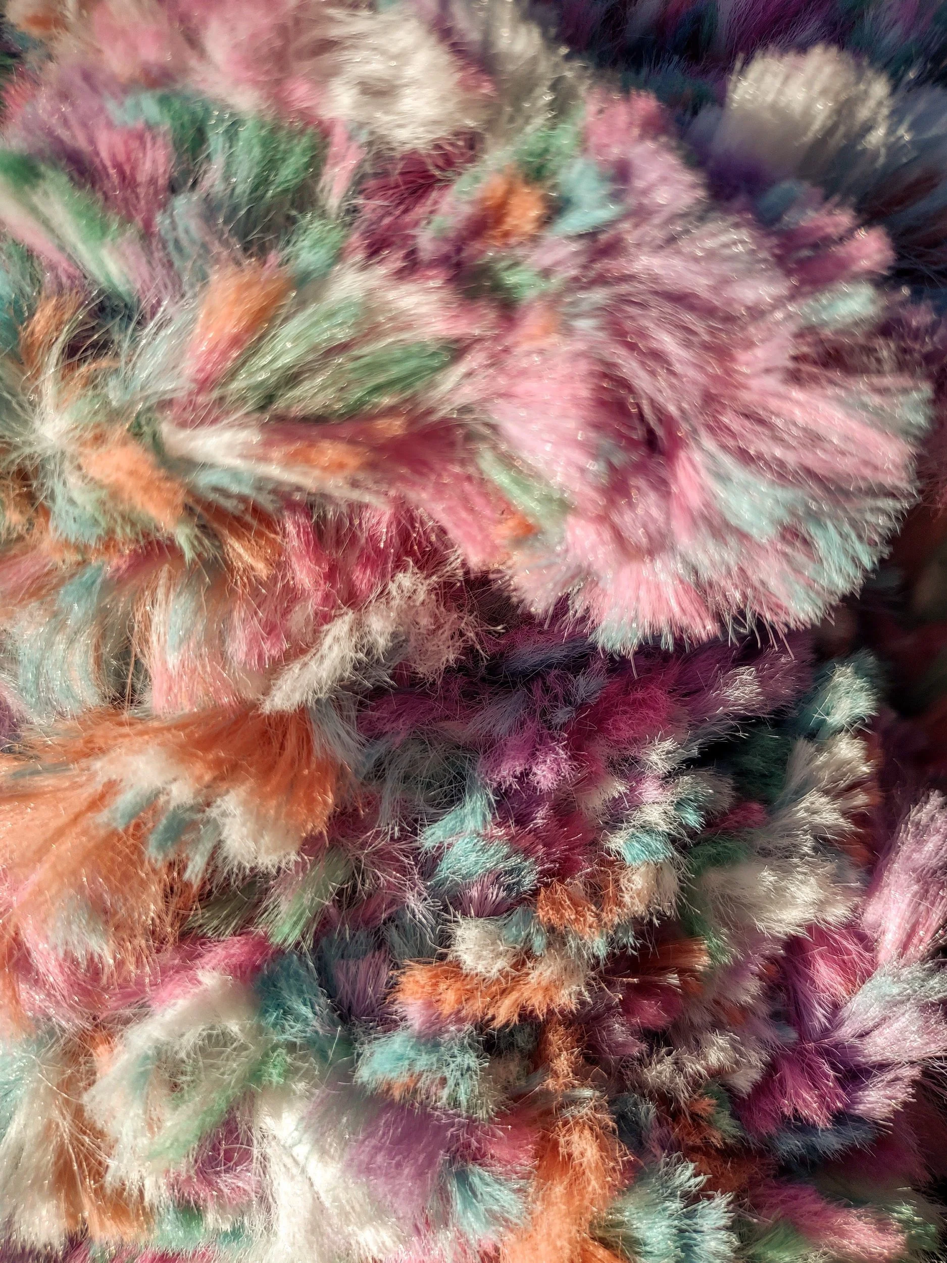 An extreme close-up of a multicolored knit scarf, showing detailed fibers and fluffy texture in pink, teal, orange, purple, and white.
