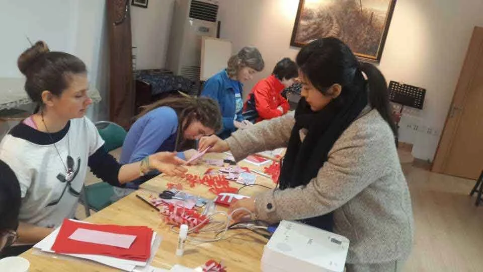 Artist Jia Bingjie (贾冰洁), a former student of Le Xi (奚乐), leading a traditional Chinese paper-cutting workshop for American students, translating folk art through a contemporary lens.