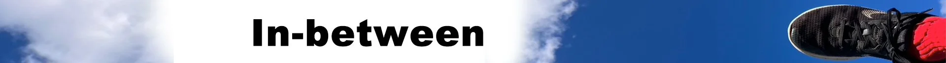 Text on a sign reads 'In-between' with a blue sky and some clouds in the background.