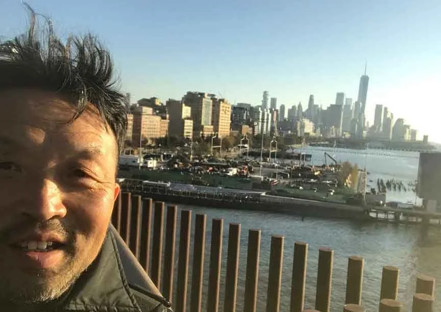 Contemporary artist Le Xi 奚乐 photographed outside the Whitney Museum of American Art, with the Manhattan skyline in the background—reflecting his artistic inquiry into urban space, perception, and the relationship between environment and self.