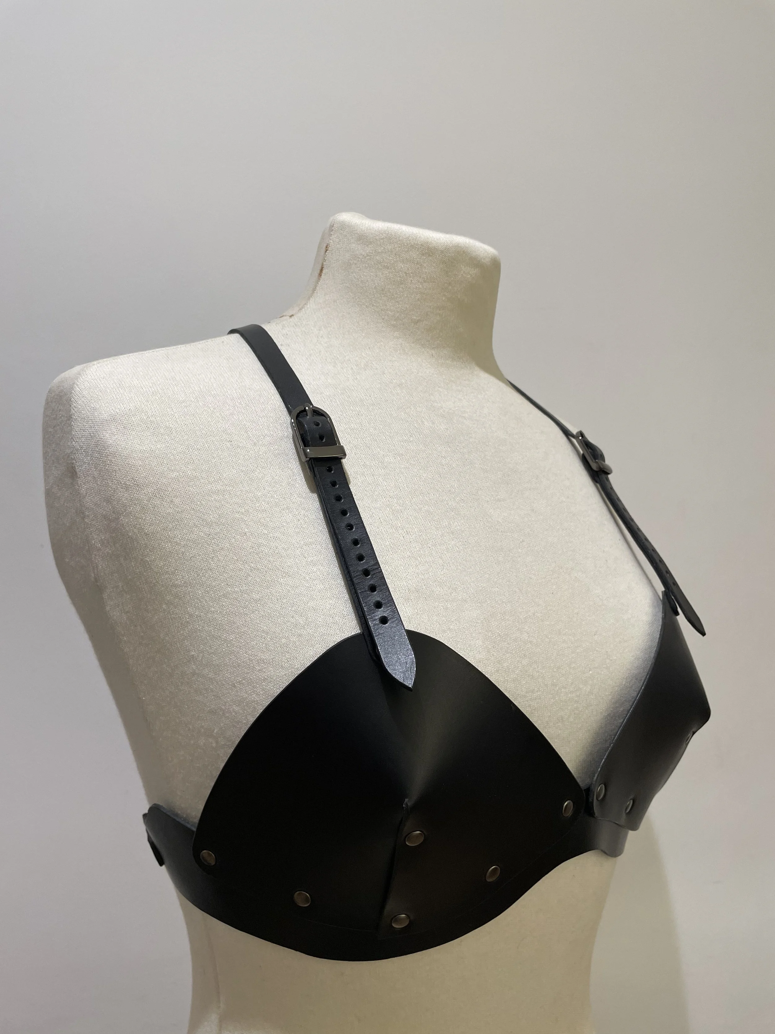 A mannequin torso wearing a black strap with a small knife attached.