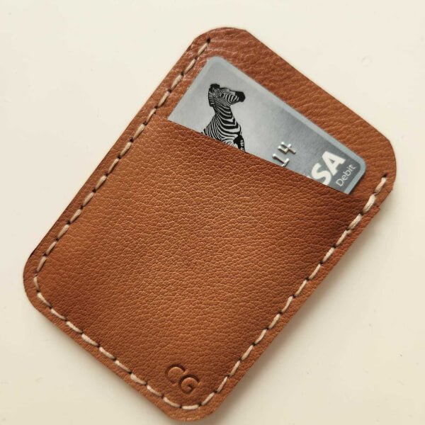 A leather cardholder with a partially visible credit card inside.