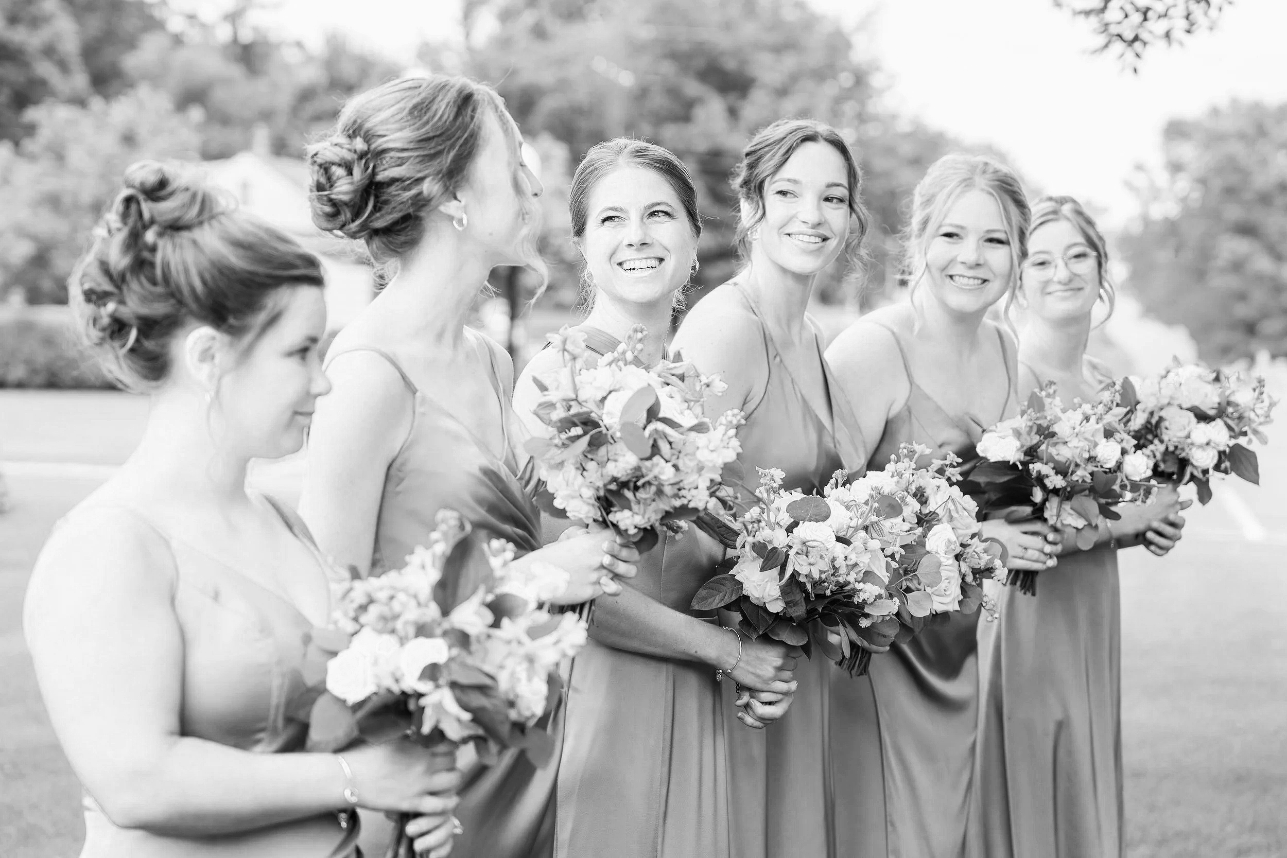 Six bridesmaids in matching light blue dresses holding bouquets of flowers standing outdoors during a wedding, photographed by Minnesota based wedding photographer, LKW Photography.