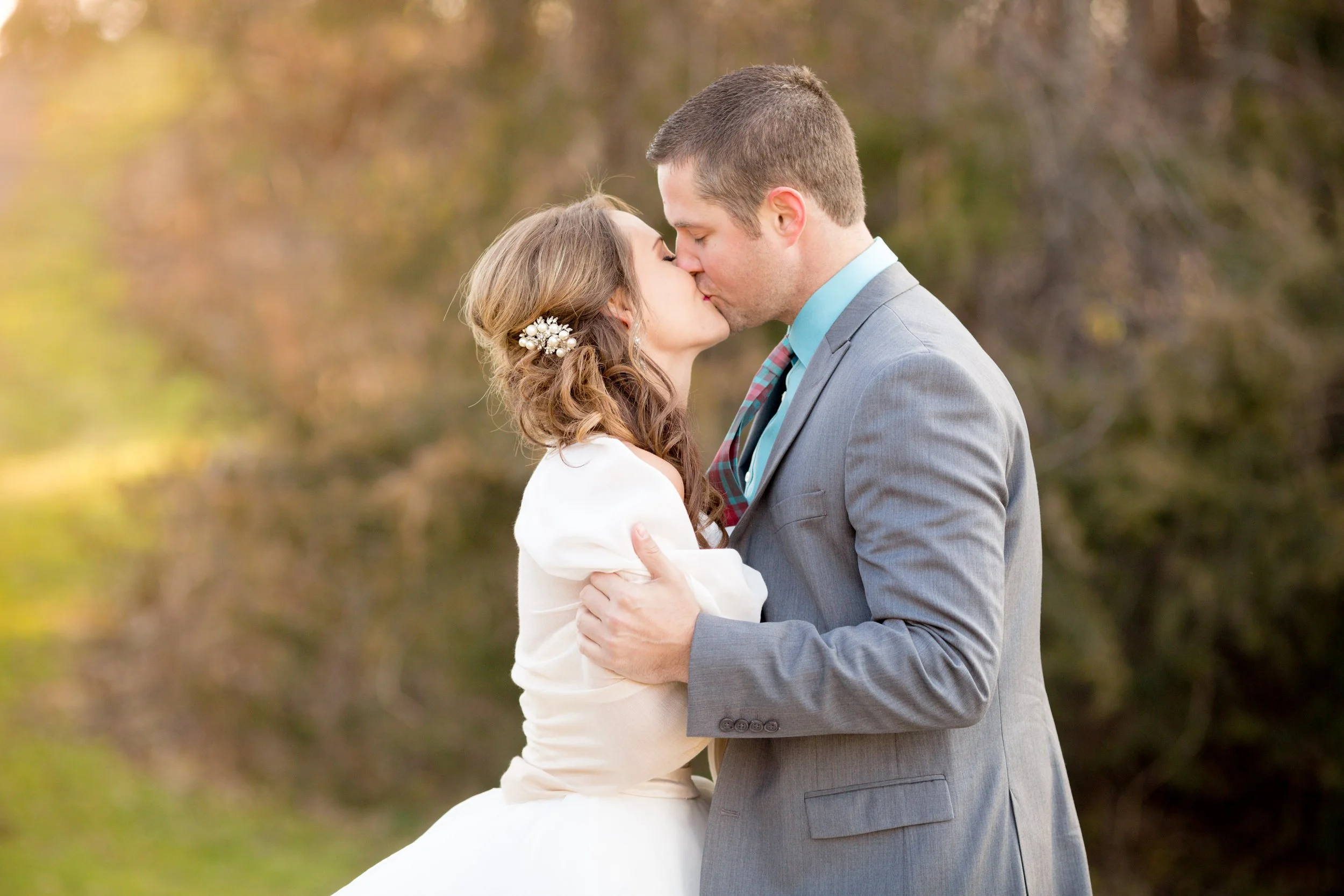Minnesota based photographer, LKW Photography, photographs a bride and groom, on their wedding day, sharing a kiss outdoors during daytime.