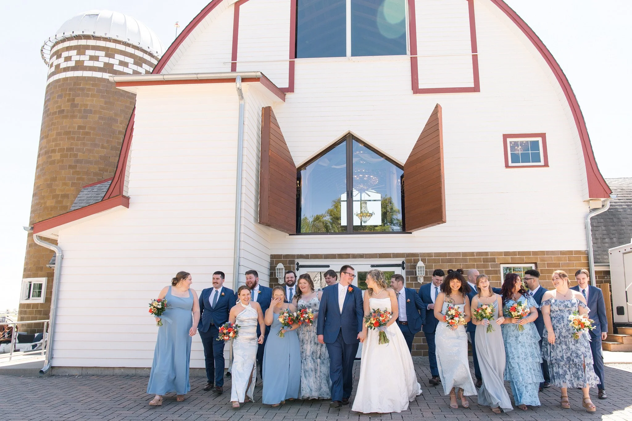 Large wedding party in shades of blue, walking towards the camera at Green Acres Events.