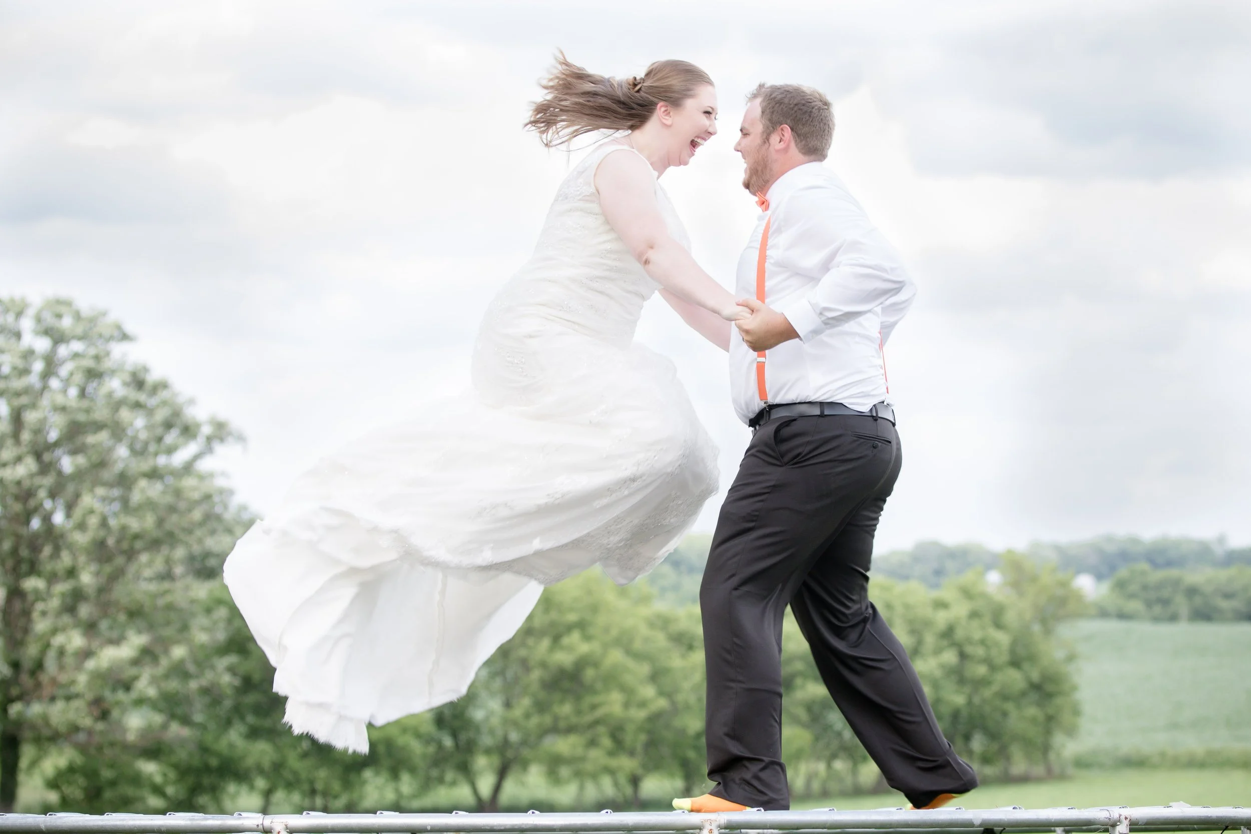 Bride and Groom jumping on a trampoline on their wedding day in Wisconsin.  Photograph taken by LKW Photography out of Minnesota.